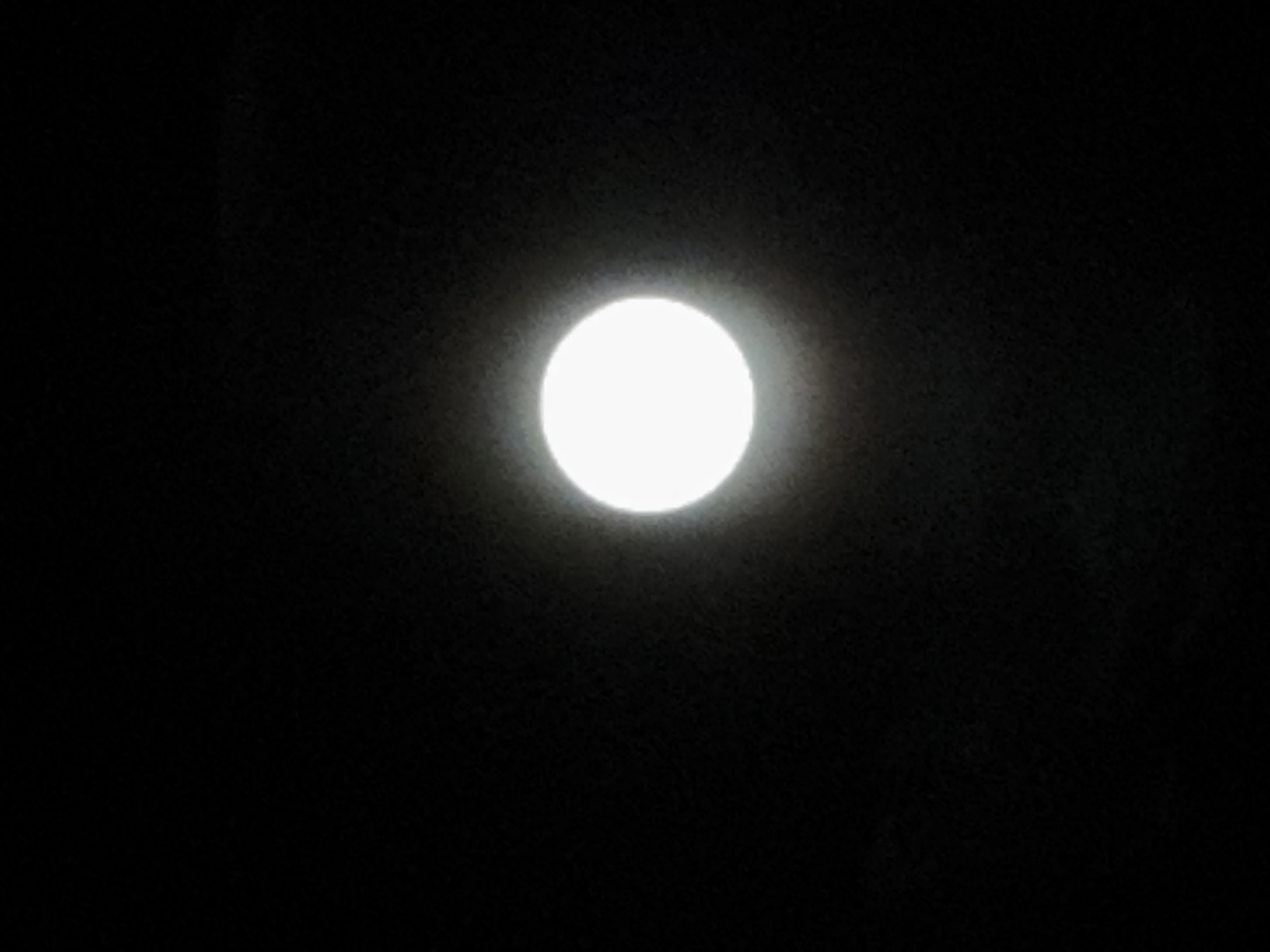 The image depicts a bright, circular light source against a dark background. Given the appearance and context, it is likely a full moon in the night sky. There is no other visible information in the image to identify the location as Paris, France, or any specific environment.