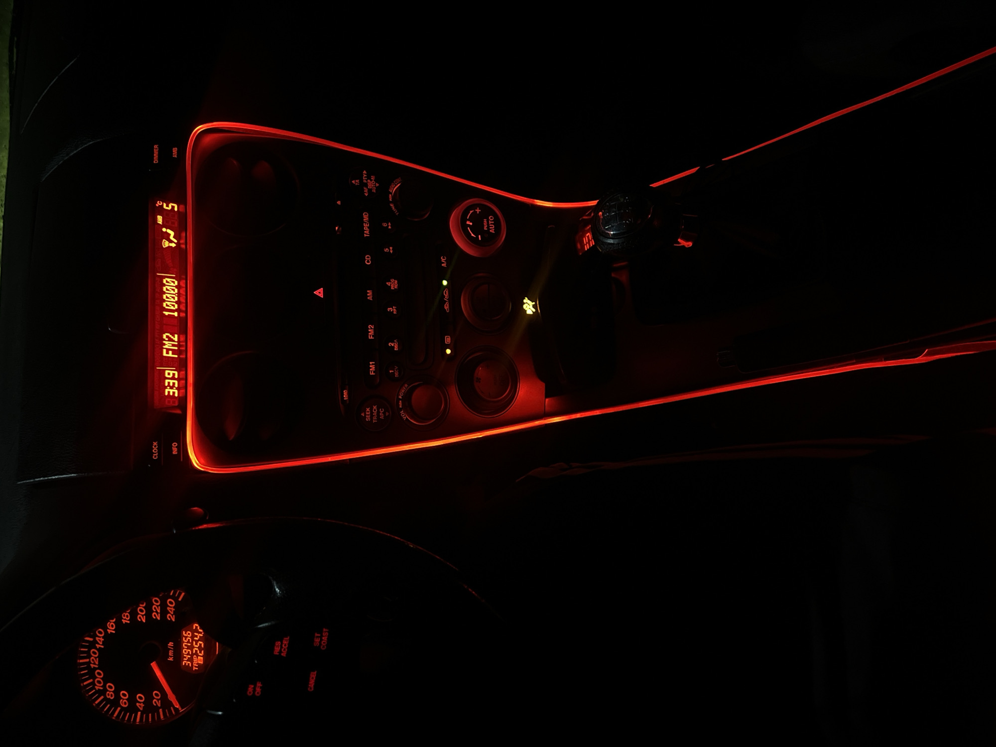 The image shows the interior of a car dashboard illuminated with red lights. The speedometer indicates a mileage of 349756 km and a trip mileage of 254.7. The radio is tuned to FM2 at 100.00 MHz, the time is 3:39, and the temperature is 5 degrees. Various car controls for the radio, air conditioning, and other functions are visible. The setting is dark, with only the illuminated elements readily discernible. There is no indication of Kribul, Bulgaria or people in the scene.