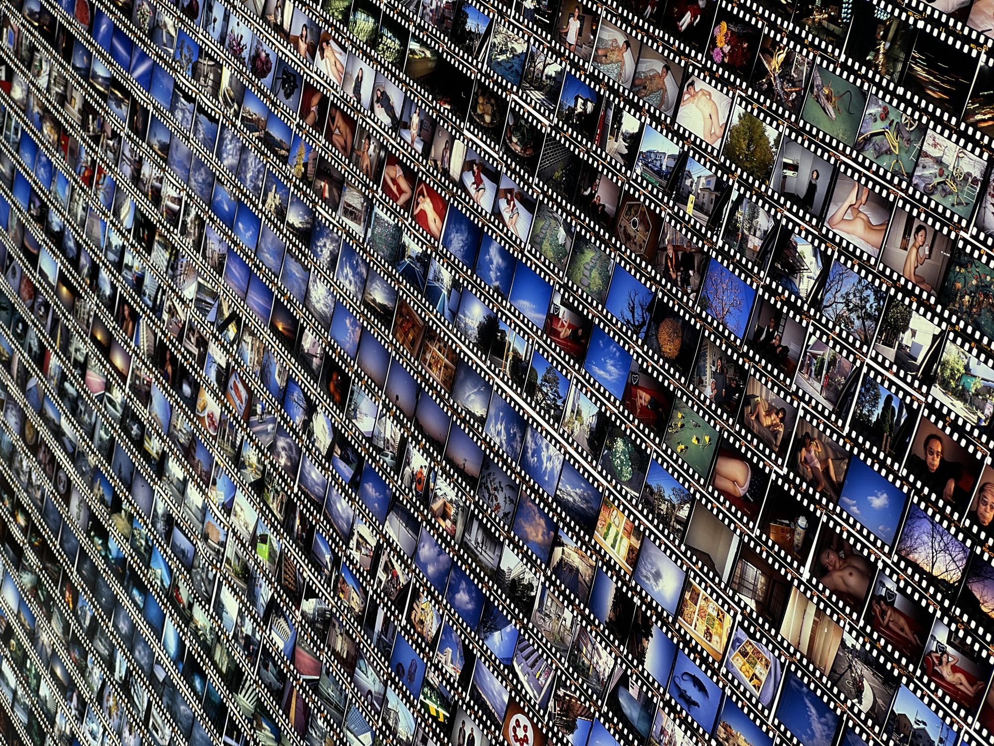 The image shows a dense grid of individual photographic frames, each appearing to be cut from a filmstrip. The frames display a variety of subjects, including: nudes, landscapes of blue skies, cityscapes, trees, buildings, personal objects, interiors, and portraits of individuals. The filmstrips are arranged diagonally, creating a visually complex pattern. There is no indication of the location of Bangkok, Thailand, in the image.