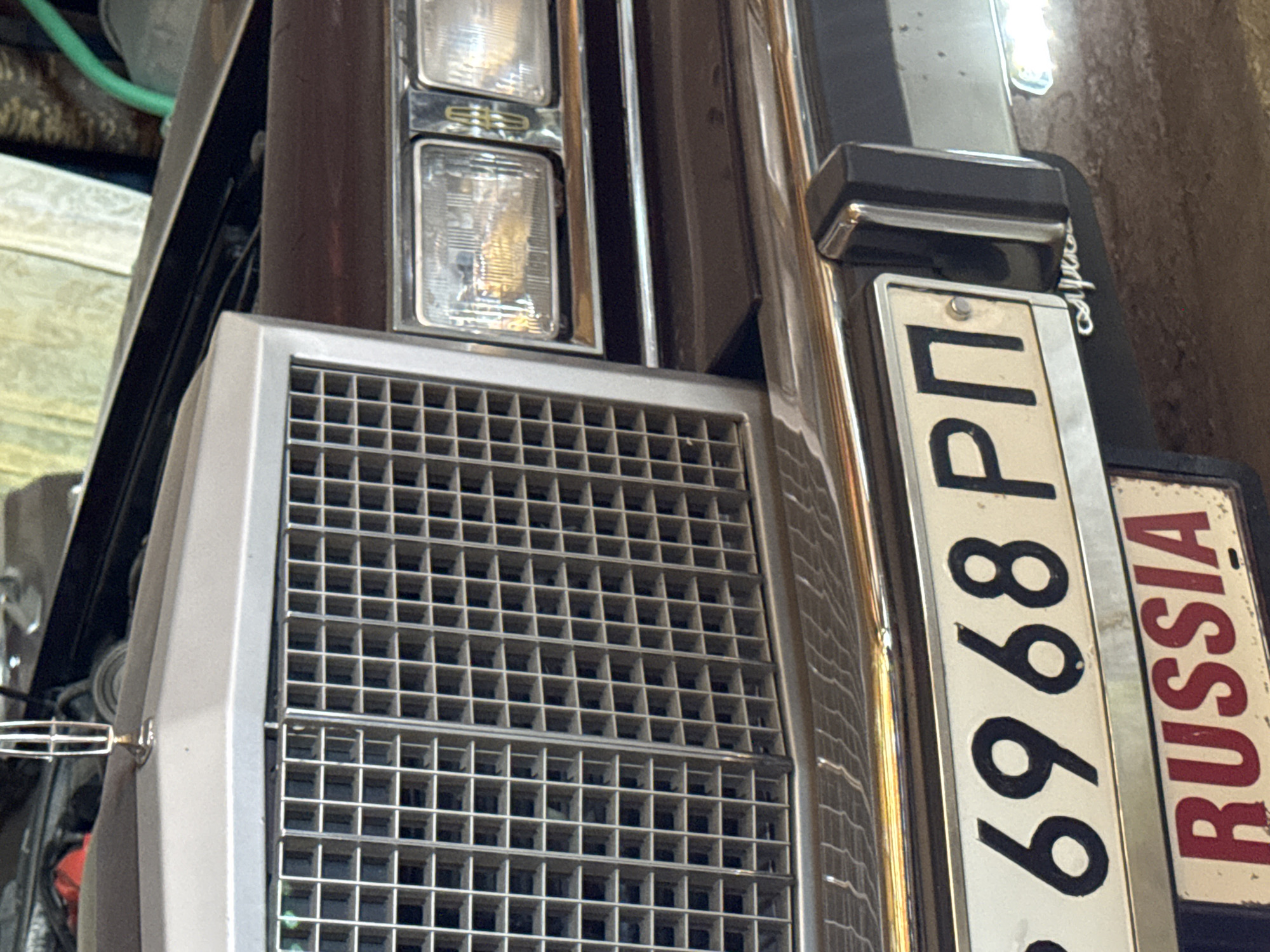The image shows a close-up of the front of a vehicle, possibly a car, featuring a silver grill, headlights, and a license plate that reads "6968 РП" with "RUSSIA" visible on a sign next to it. The license plate suggests the vehicle is registered in Russia. There is no specific indication of the location being in Chaikovsky, Russia, within the given image.
