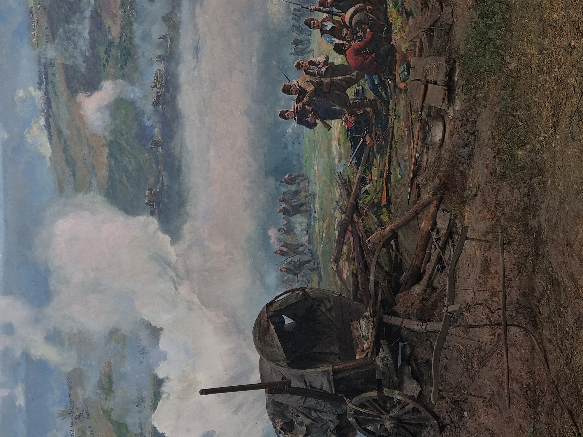 This is a detail of the Pleven Panorama, a large panoramic painting located in Pleven, Bulgaria. The artwork depicts the Siege of Pleven during the Russo-Turkish War of 1877-1878. In the foreground is a covered wagon, surrounded by broken branches and debris. In the mid-ground, groups of soldiers with rifles and swords are engaged in combat. In the background, a landscape of rolling hills and smoke-filled skies stretches to the horizon.
