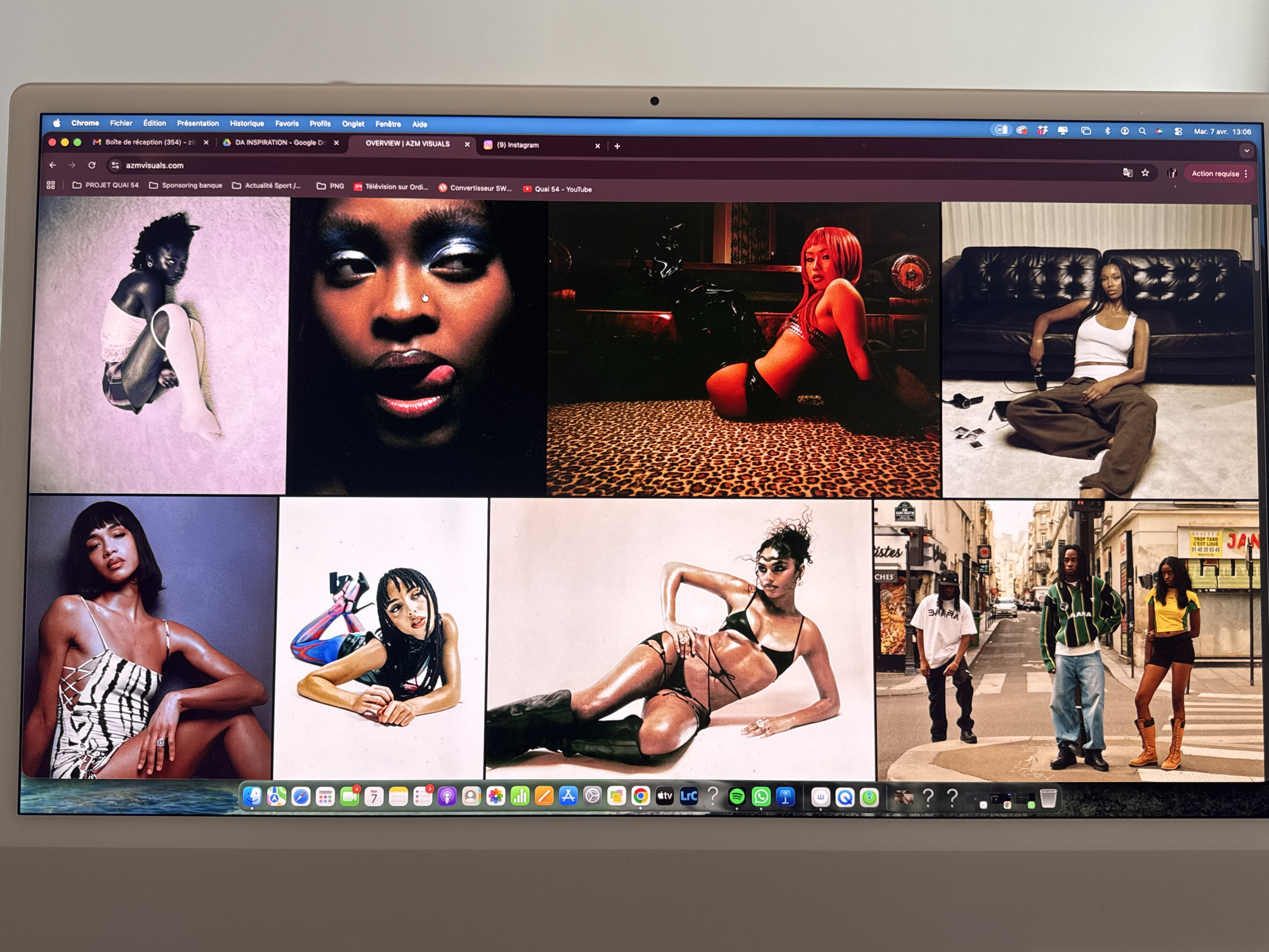 A laptop screen displays the azmvisuals.com website, showcasing a collection of fashion and portrait photographs. The website's interface features a variety of images of people dressed in different styles and poses. The top row includes images of individuals in lingerie, close-up portraits, and women in various seated positions. The bottom row contains more fashion shots, including images of models in elaborate outfits and a street scene with three people standing in the middle of a street in Montreuil, France. The street scene has a vintage feel, with old storefronts and signage, including a "REALTY TROP TARD" sign and what appears to be a "JAN" sign with phone numbers below. The laptop's dock at the bottom of the screen displays various app icons. The browser tabs indicate the user is also viewing their email inbox, Google Drive, Instagram, and YouTube. A date and time stamp on the upper right corner shows "Mar. 7 avr. 13:06".