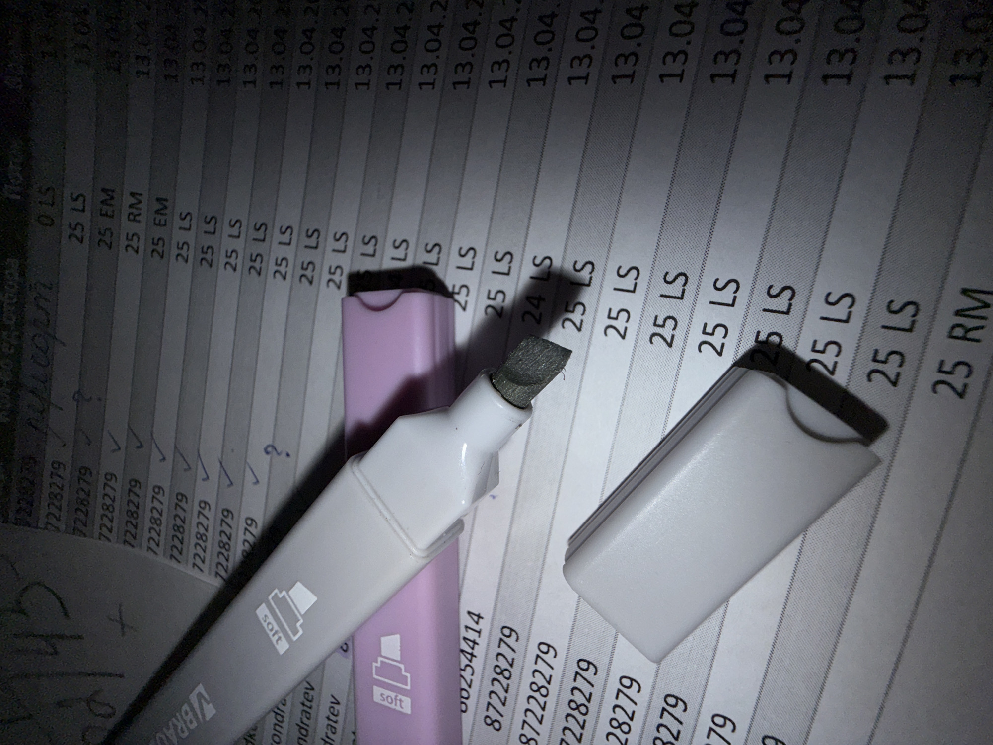 The image shows a close-up view of a document with a highlighter. The document appears to be a list, possibly a spreadsheet or a ledger, with rows containing the number "7228279" and various codes like "25 LS," "25 EM," and "25 RM," along with dates formatted as "13.04.20". Some rows are marked with check marks or question marks. A gray "BRAUBERG" highlighter with a gray tip is lying on the document. The highlighter's cap is next to it. The overall lighting is dim. The city of Lupanovo, Russia is not discernible in the image.