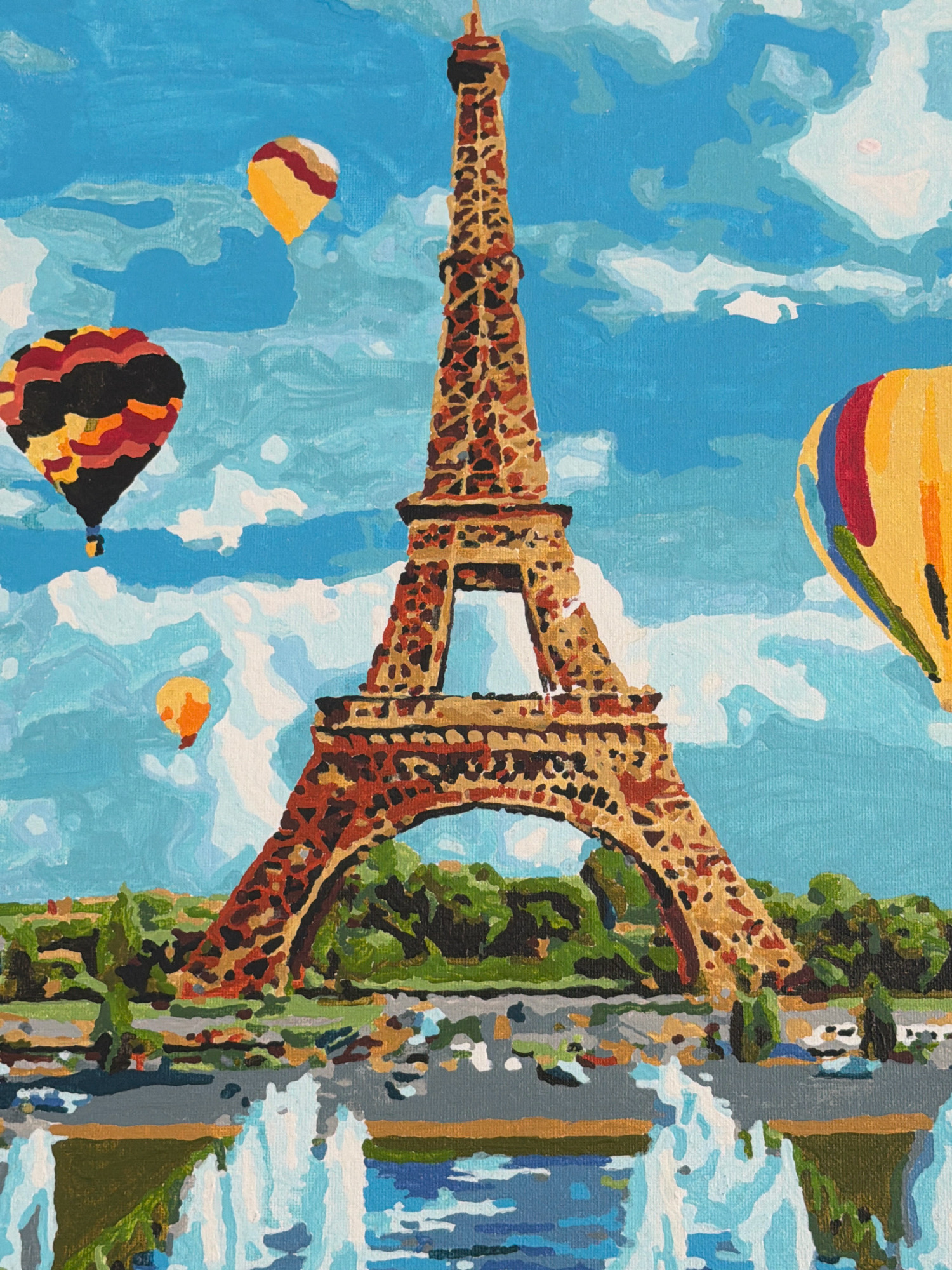 The image is a painting depicting the Eiffel Tower in Paris, France, with several hot air balloons in the sky and a reflection of the tower and the surrounding greenery in what appears to be a body of water with fountains. The painting style is reminiscent of paint-by-numbers, with distinct blocks of color and simplified shapes. The Eiffel Tower is the central subject, rendered in shades of brown and orange. To the left of the tower, there are two hot air balloons, one with a dark and colorful pattern and another smaller one in orange. To the right, a larger yellow hot air balloon with red and blue stripes is visible. The background is a bright blue sky with white and light blue clouds. The lower part of the painting shows a green landscape with trees and a body of water with white fountain spray. The painting does not depict any people or specific actions, focusing instead on the iconic landmark and its scenic surroundings. The location is Paris, France, not Kyiv, Ukraine.