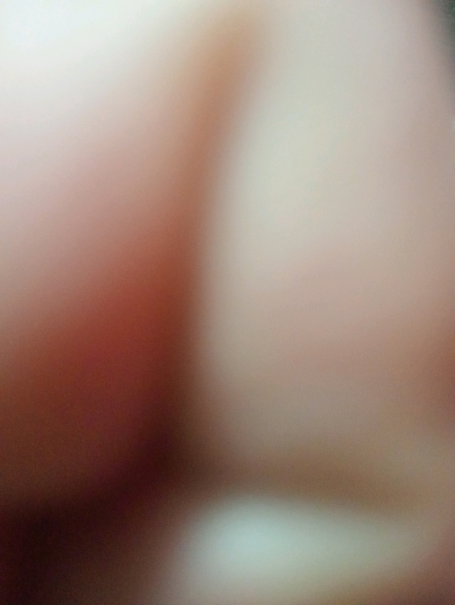The image is an out-of-focus, close-up view of skin. There are no discernible objects, people, or environmental features visible. The lighting suggests a soft, diffused light source, and the colors are predominantly warm tones of peach and brown, with a lighter, almost white area on the right side. No location in Parça Xələc, Azerbaijan, can be identified from this image.