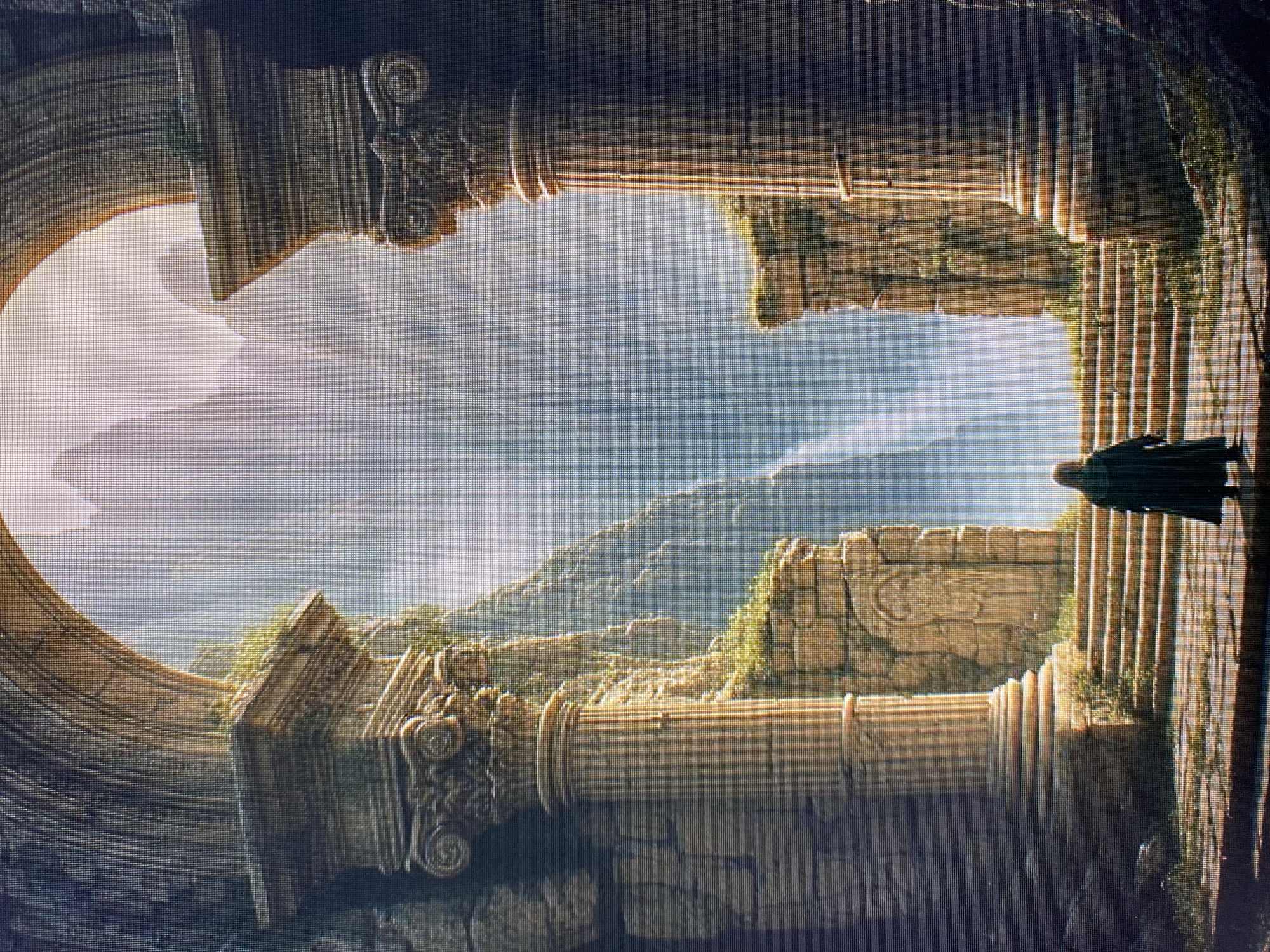 The image depicts a cinematic, fantasy-inspired scene featuring ancient ruins and a lone figure. The setting appears to be a mountainous landscape viewed through a large, arched opening supported by ornate classical columns. The ruins themselves are made of weathered stone, with intricate carvings and sections of overgrown vegetation, suggesting a place lost to time. Sunlight streams through the archway, illuminating the textured surfaces of the architecture and casting soft shadows.
A figure, cloaked in dark green or black, stands on a stone staircase to the right of the frame, looking out at the vista. Their posture and the dramatic lighting create a sense of contemplation or perhaps anticipation. The background shows rolling hills and distant mountains shrouded in a light mist, with a bright, overcast sky. The overall mood is one of quiet grandeur, mystery, and a touch of melancholy. The time of day appears to be daytime, with diffused sunlight. No text is visible in the image.