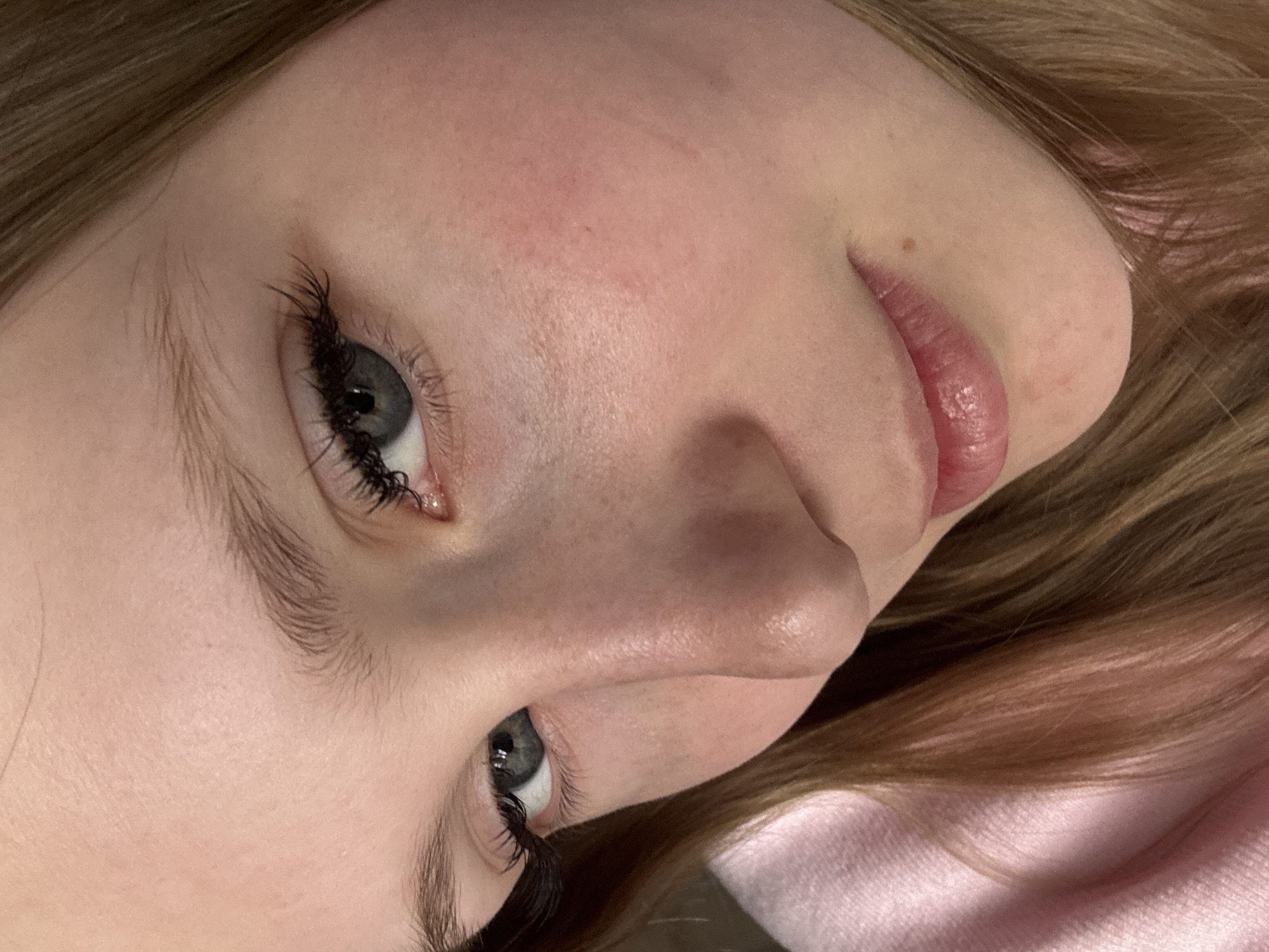 A close-up, angled view of a person's face. The person has light skin, light brown hair, and gray eyes with dark eyelashes. The person is wearing a light pink garment. No information suggests this photo was taken in Chaikovsky, Russia.