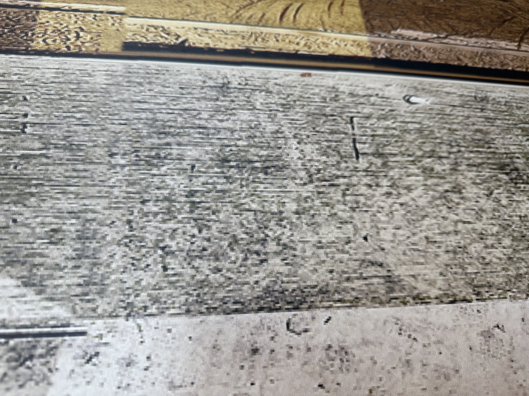 The image shows a close-up view of a surface. The surface has a wood grain pattern with grey and white tones. There is a raised rectangular detail above the main surface. A small reddish stain or marking is visible near the top center. A vertical line or groove is visible slightly right of the image's center. The blurred image quality obscures clear details.
Moscow, Russia is not discernible from the information present in the image.