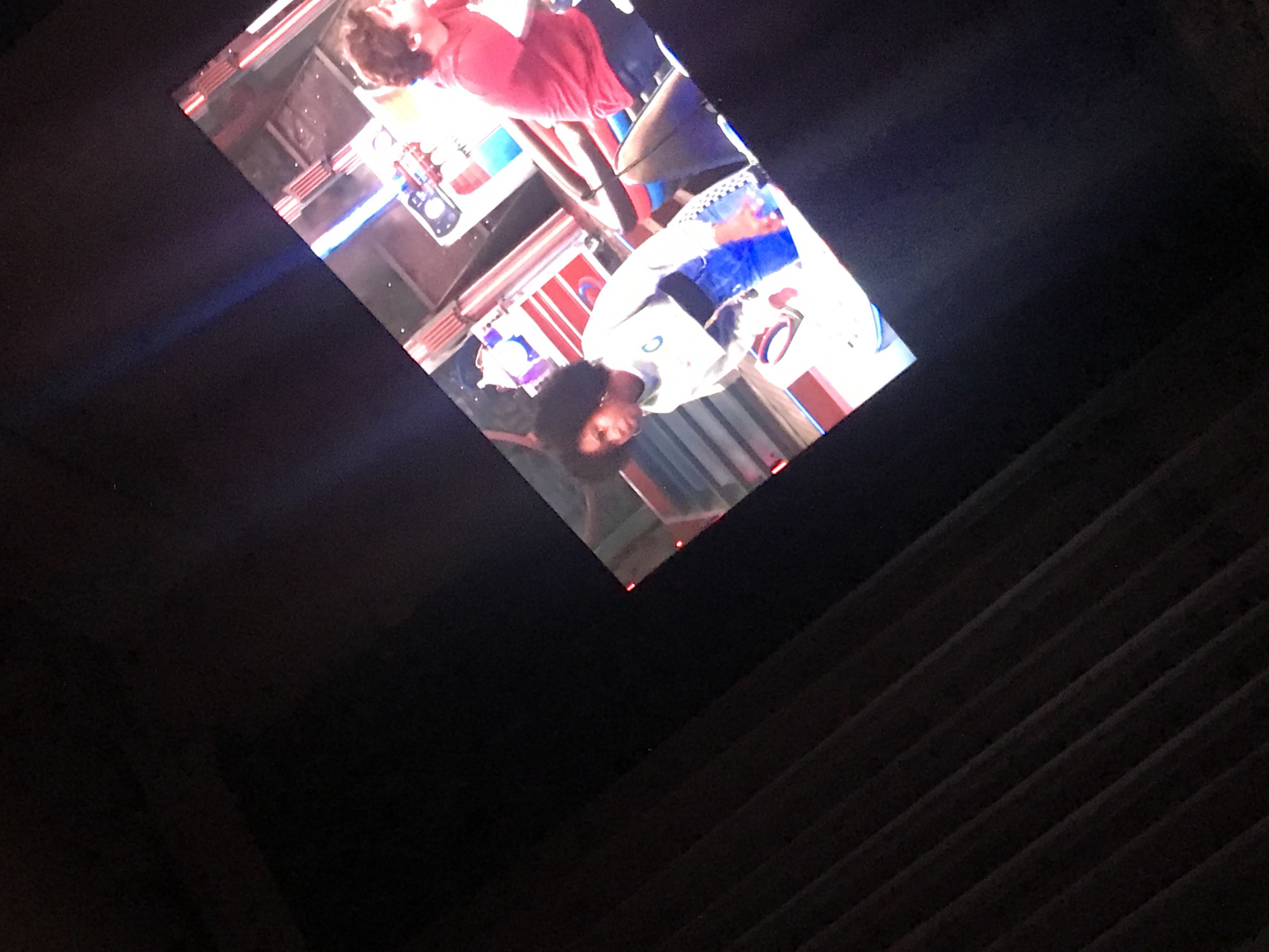 The image appears to be a photograph of a television screen, possibly taken in a darkened room. On the screen, there are two individuals, with one wearing a red shirt and the other wearing a white and blue shirt. The scene suggests an indoor setting, with various objects and colorful elements visible in the background. The rest of the image consists of a dark background. I cannot provide details on the location in Yerevan, Armenia, as the image does not offer enough detail.