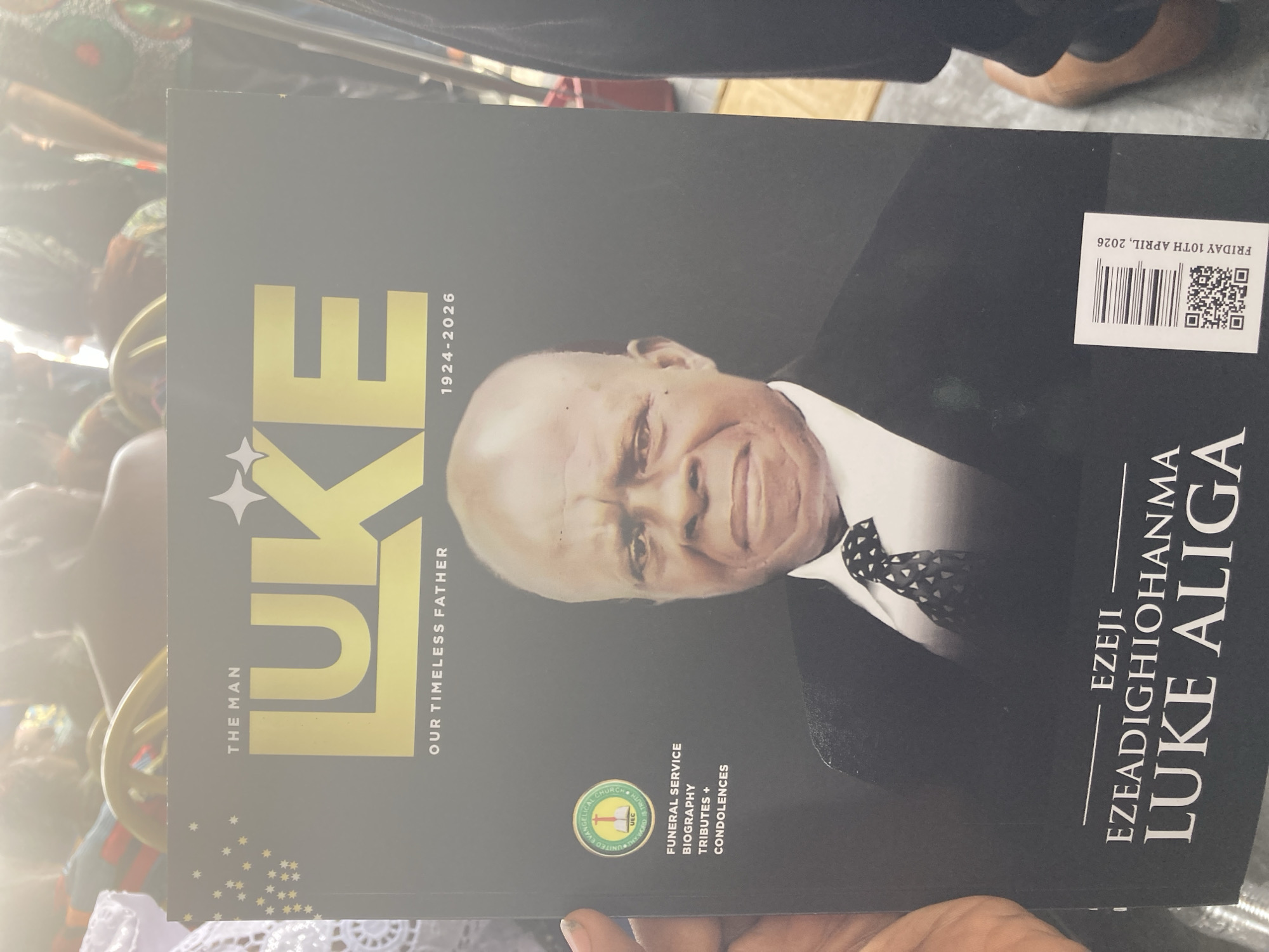 A program memorializing Ezeji Ezeadighiohanma Luke Aliga is held. The program is dated for Friday, April 10, 2026. Aliga was born in 1924 and died in 2026. The program includes a biography, tributes, and condolences. The memorial program is put on by the United Evangelical Church. The location where the image was taken is Nnenu, Nigeria.
