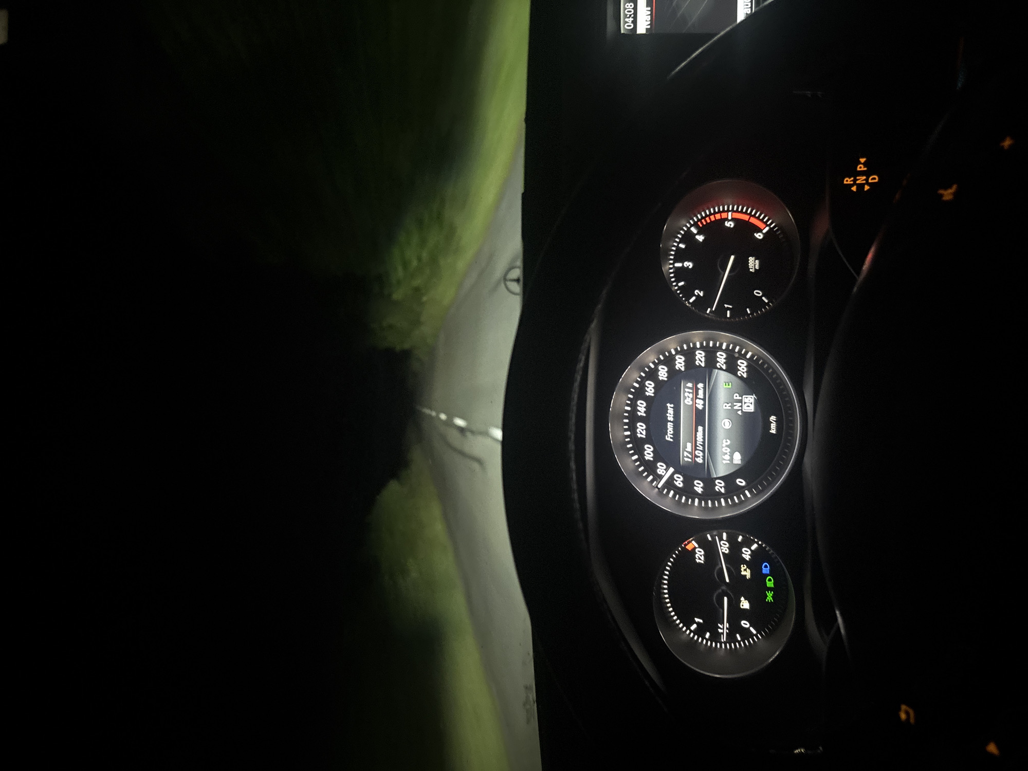 The image depicts a car interior at night. The dashboard is visible, showing a speedometer reading approximately 48 km/h, with the gear selector in 'N' (Neutral) or 'P' (Park). The ambient temperature is displayed as 16 degrees Celsius. The odometer indicates a distance of 17 km. The outside view through the windshield reveals a dark road with grass on either side, illuminated by the car's headlights. There is no information to suggest this location is Tankovo, Bulgaria.