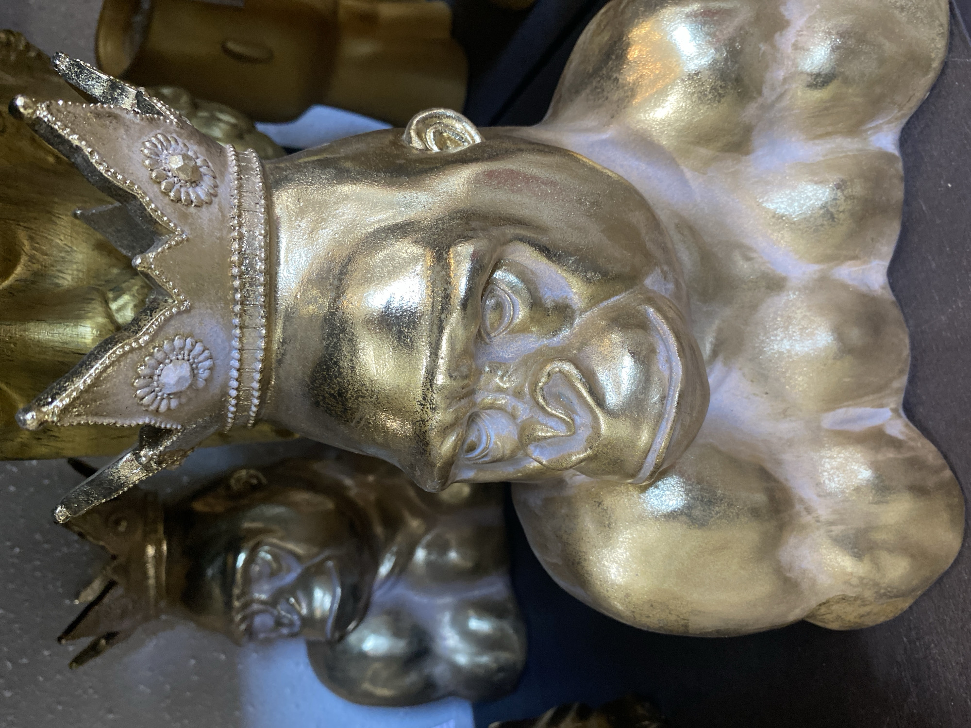A close-up shows a golden sculpture of a crowned head and torso. Another similar sculpture lies partially visible in the background. The sculptures sit on a dark surface. This photograph was taken in Yekaterinburg, Russia.