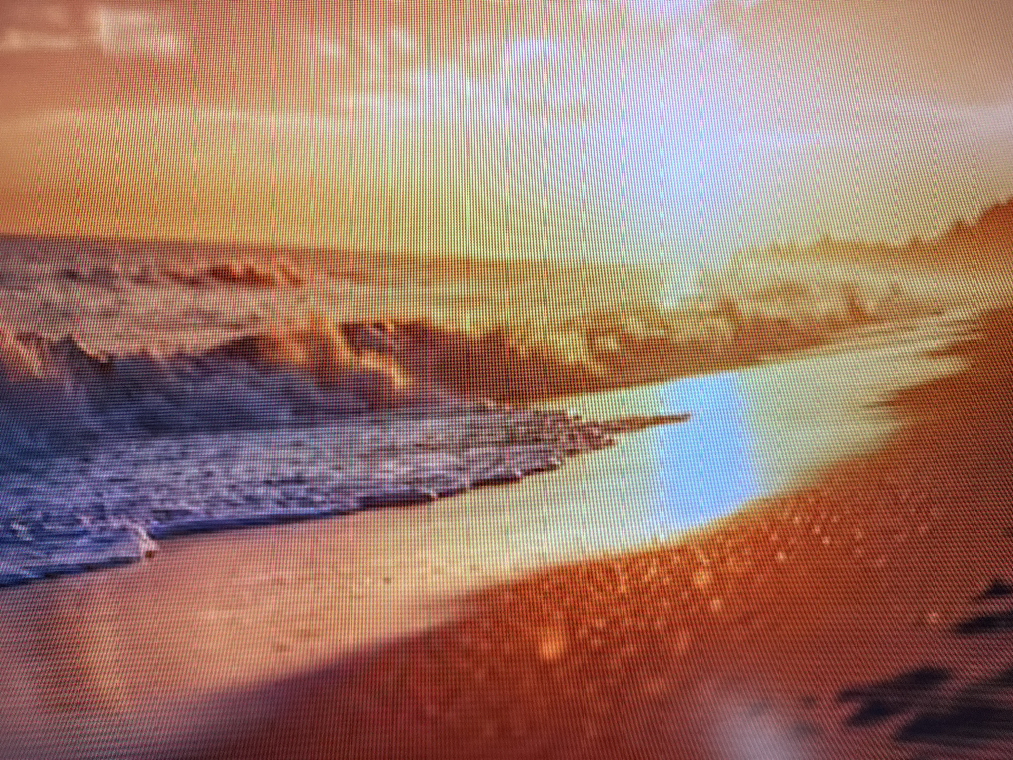 This media file depicts a serene beach scene at sunset. The low angle of the sun casts a warm, golden light across the sky, which is filled with soft, diffused clouds. Waves are gently rolling onto the sandy shore, creating a reflective surface on the wet sand that mirrors the colors of the sky. The overall mood is peaceful and tranquil, evoking a sense of calm.
The primary subjects are the natural elements of the beach: the ocean, the sand, and the sky. There are no visible people or man-made objects that are clearly distinguishable. The setting is a beach, likely a coastal area, given the presence of waves and the expanse of the ocean meeting the sky.
The time of day is clearly sunset, as indicated by the warm, low-angled sunlight and the colors in the sky. The weather appears calm and clear, with soft clouds that are illuminated by the setting sun. There are no explicit location cues in the image itself that would pinpoint it to Szczecin, Poland, other than the provided context.
Notable details include the vibrant orange and yellow hues dominating the scene, transitioning to softer blues and whites in the sky and water. The texture of the sand, with its varying shades of orange and brown, is also noticeable. The reflections on the wet sand add depth and visual interest. There is no visible text within the image.