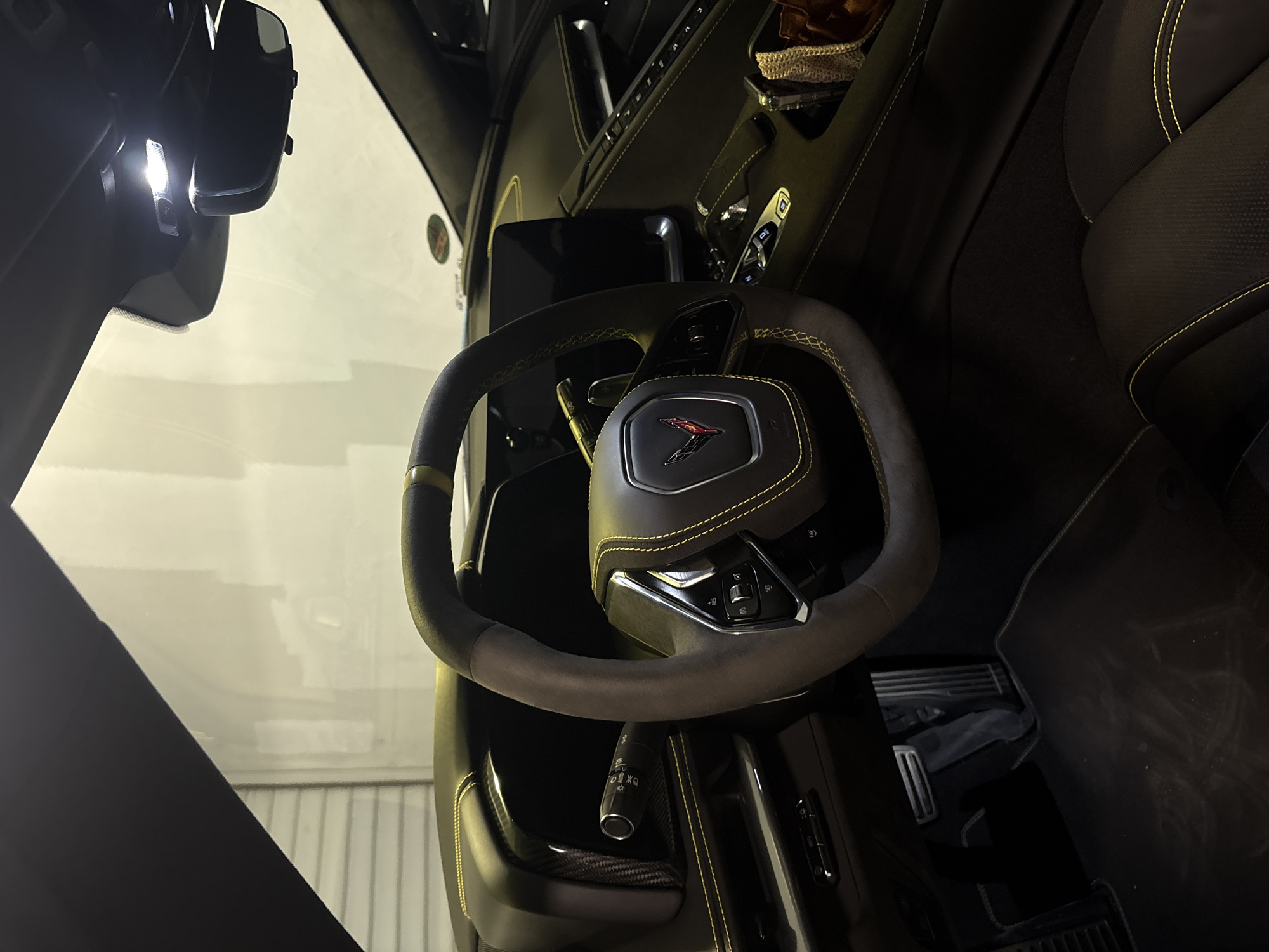 The image shows the interior of a car, focusing on the steering wheel, dashboard, and front passenger seat. The steering wheel has a distinct emblem in the center and yellow stitching. The dashboard is partially visible with various controls. The passenger seat is dark with yellow stitching. The rearview mirror and a portion of the windshield are also visible. The image does not contain sufficient detail to determine the location in Varna, Bulgaria.