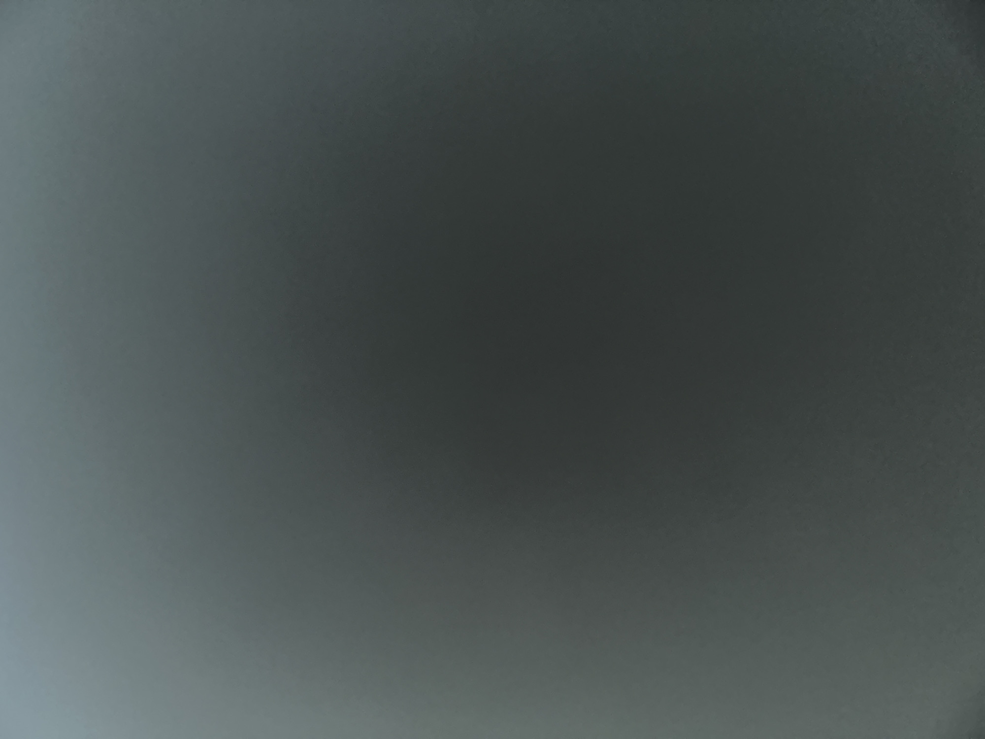 This is a plain, gray, abstract image with no discernible subjects, objects, or scene. There is no activity or event taking place. The image is uniformly colored with a gradient from a lighter gray at the bottom to a darker gray at the top, suggesting it might be a textured surface or a lighting effect. There are no visible details such as time of day, weather, location cues, emotions, or text. The image is likely a texture, a background, or an out-of-focus shot.