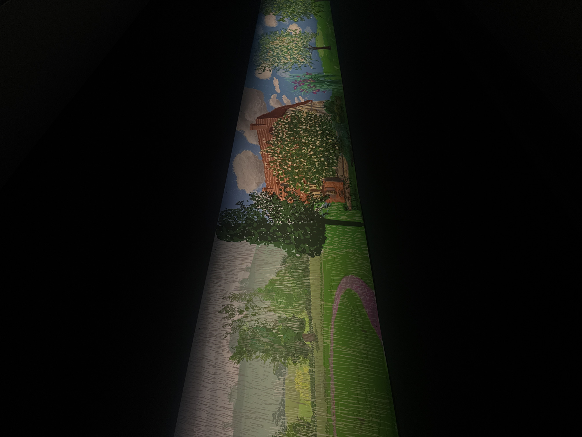 The image displays a section of a mural painted on a curved surface, likely a wall or a cylindrical structure, within a dark environment. The mural depicts a serene, idyllic landscape.
The upper portion of the mural features a red-roofed building, possibly a house or a barn, nestled amongst abundant flowering trees. The trees are adorned with masses of small white blossoms, suggesting springtime. Above, a bright blue sky is dotted with fluffy white clouds. In the background, there are hints of a wooden fence and tall purple irises.
Moving down the mural, the scene transitions to a park-like setting with lush green grass. A winding, light purple path curves through the lawn. Several trees with dense green foliage are scattered across the landscape, some appearing mature and others younger. In the middle ground, there's a suggestion of a body of water or mist, rendered with vertical, greyish brushstrokes, creating a soft, hazy effect. Further in the distance, hints of yellow flowers can be seen. The overall style of the mural is somewhat impressionistic, with a focus on color and light rather than sharp detail. The painting evokes a feeling of peacefulness and natural beauty. No people or text are visible in the depicted section of the mural. The lighting suggests the mural is indoors, illuminated, while the surroundings are dark.
