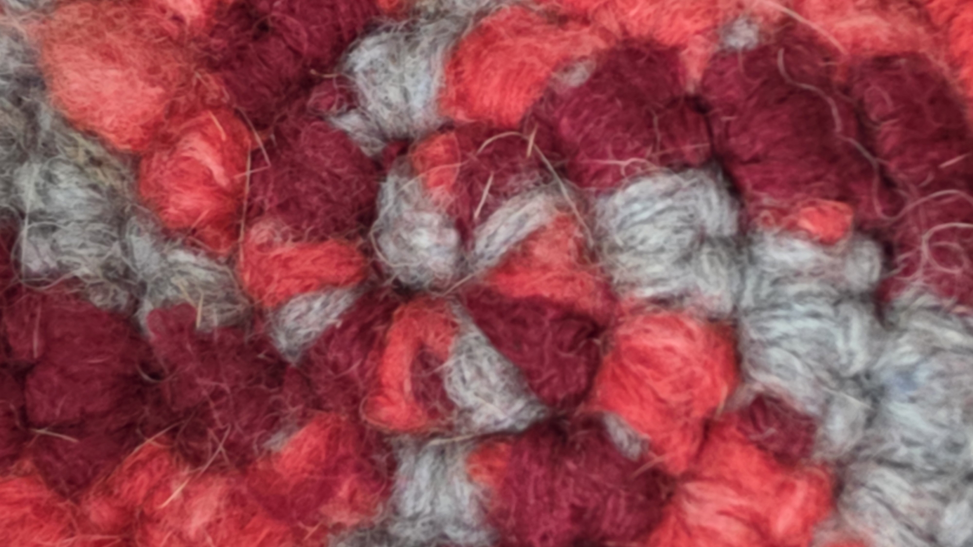 The image shows a close-up view of a woolen texture. The dominant colors are shades of red and gray. The texture appears to be thick and somewhat fuzzy. There is no indication that this image is related to Saint Petersburg, Russia.