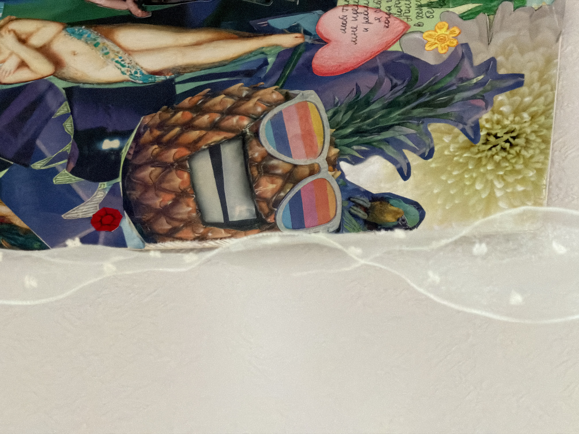 The image is a collage of various cut-out images. The composition includes a partially nude woman reclining, a pineapple wearing rainbow sunglasses, a red heart with Cyrillic writing, flowers (including a yellow daffodil and a white chrysanthemum), and blue and purple patterned paper. The background is predominantly white with subtle shadows and textures, suggesting a textured surface. The overall arrangement gives a surreal and whimsical impression.