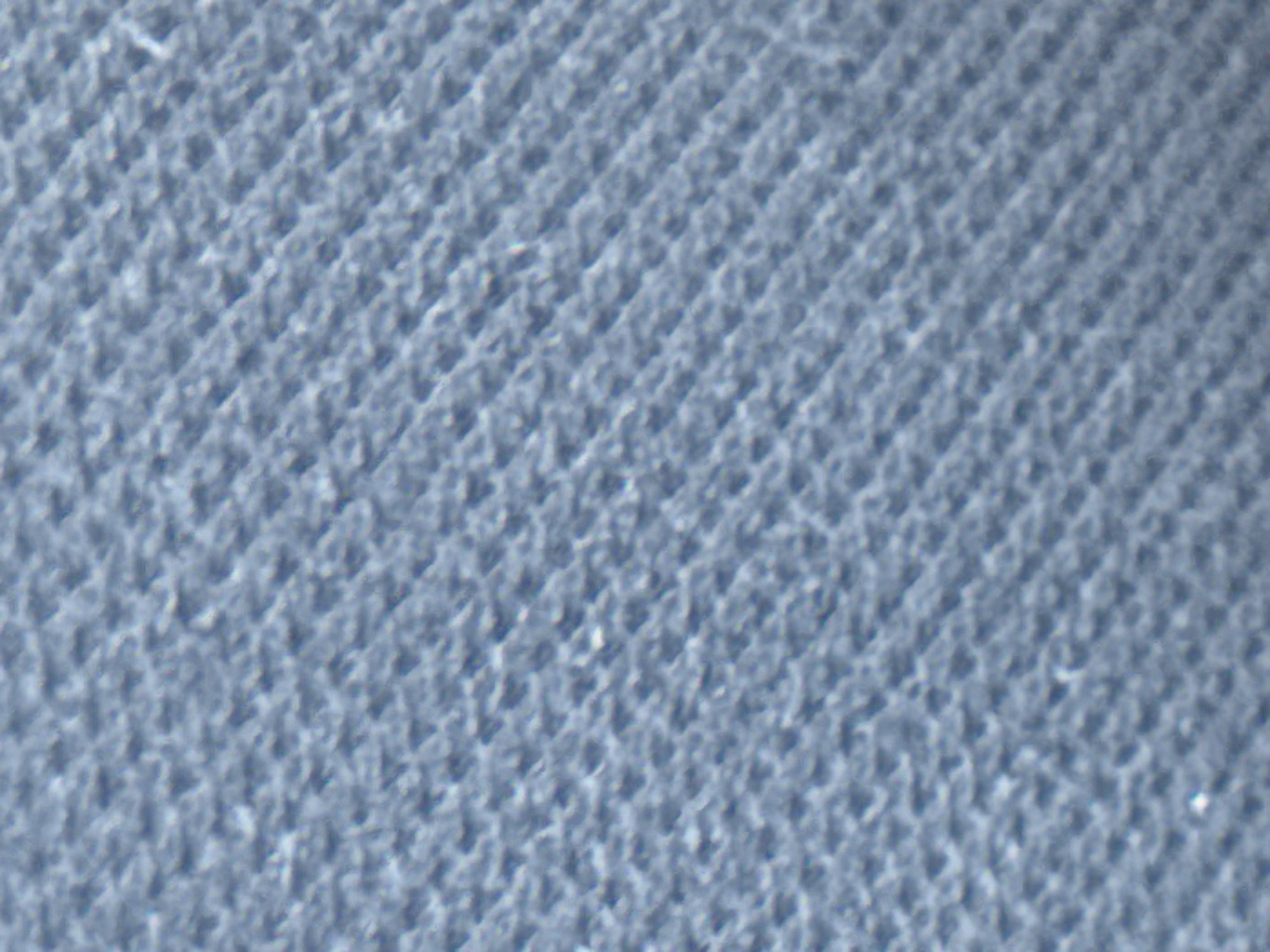 The image shows a close-up, out-of-focus view of a blue, textured surface. The texture appears to be woven or knitted, with diagonal lines forming a repeating pattern. There are no discernible people, objects, or actions in the image. The scene is entirely abstract and lacks any contextual information to place it within the city of Varna, Bulgaria, or any other specific location.