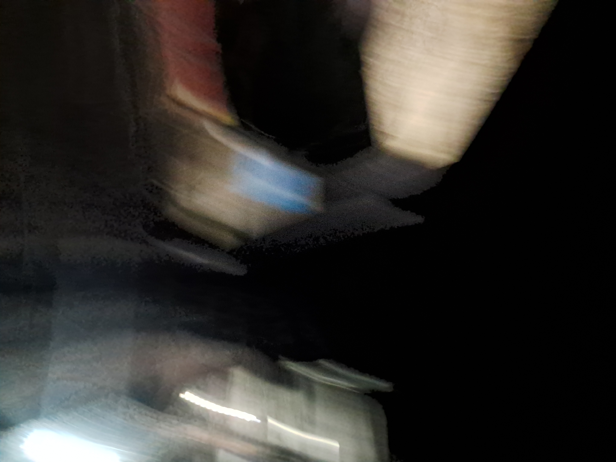The image is a blurry, abstract photograph taken at night, likely from a moving vehicle or with a shaky camera. There are streaks of light and indistinct shapes. The overall impression is one of motion and low light conditions. Without any discernible landmarks or specific context, it is impossible to determine the location within Cumana, Venezuela.