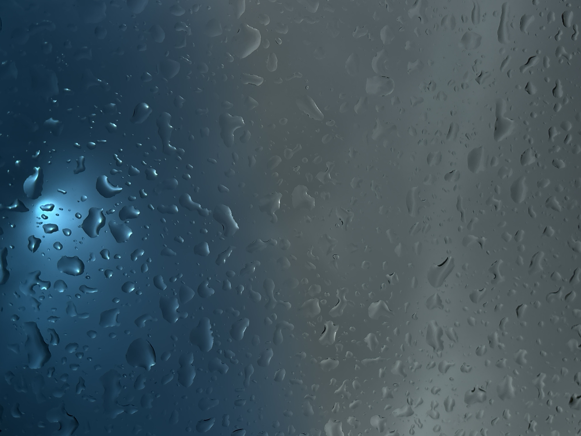 The image depicts rain droplets on a glass surface. The left side of the image is dominated by a blue hue, with more prominent and well-defined droplets. The right side transitions to a gray tone with a high density of droplets. There is no indication of the image location being in Arandjelovac Municipality, Serbia, and there are no people, objects, actions, or interactions evident in the frame.