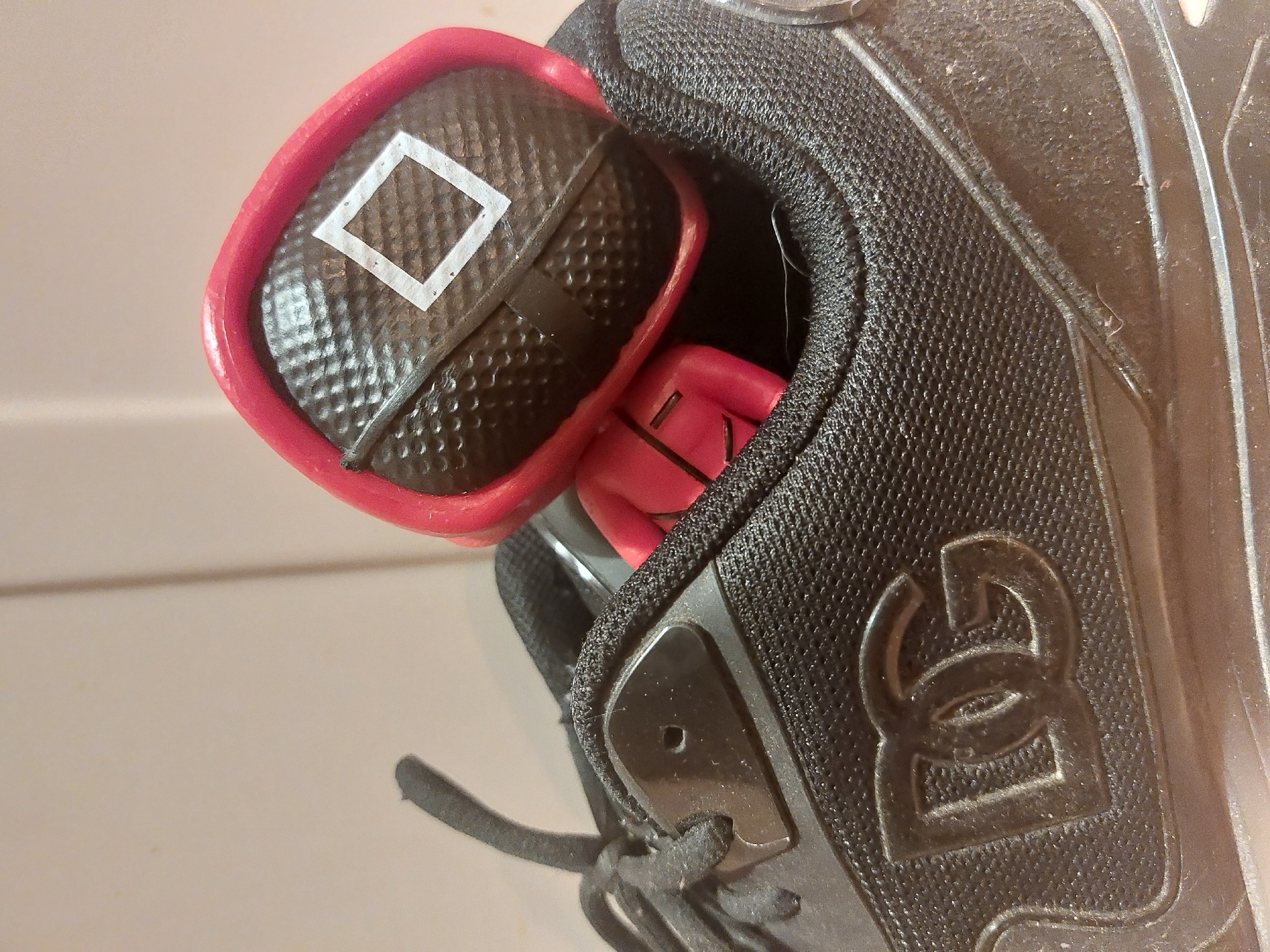 A close-up image shows a black shoe with the logo "DC" on its side. Inside the shoe is a red and black object, likely a toy, with a square symbol on the black portion. The background is blurry and provides minimal context. The location of the image is not discernible and therefore can not be traced to Tsarevo, Bulgaria.
