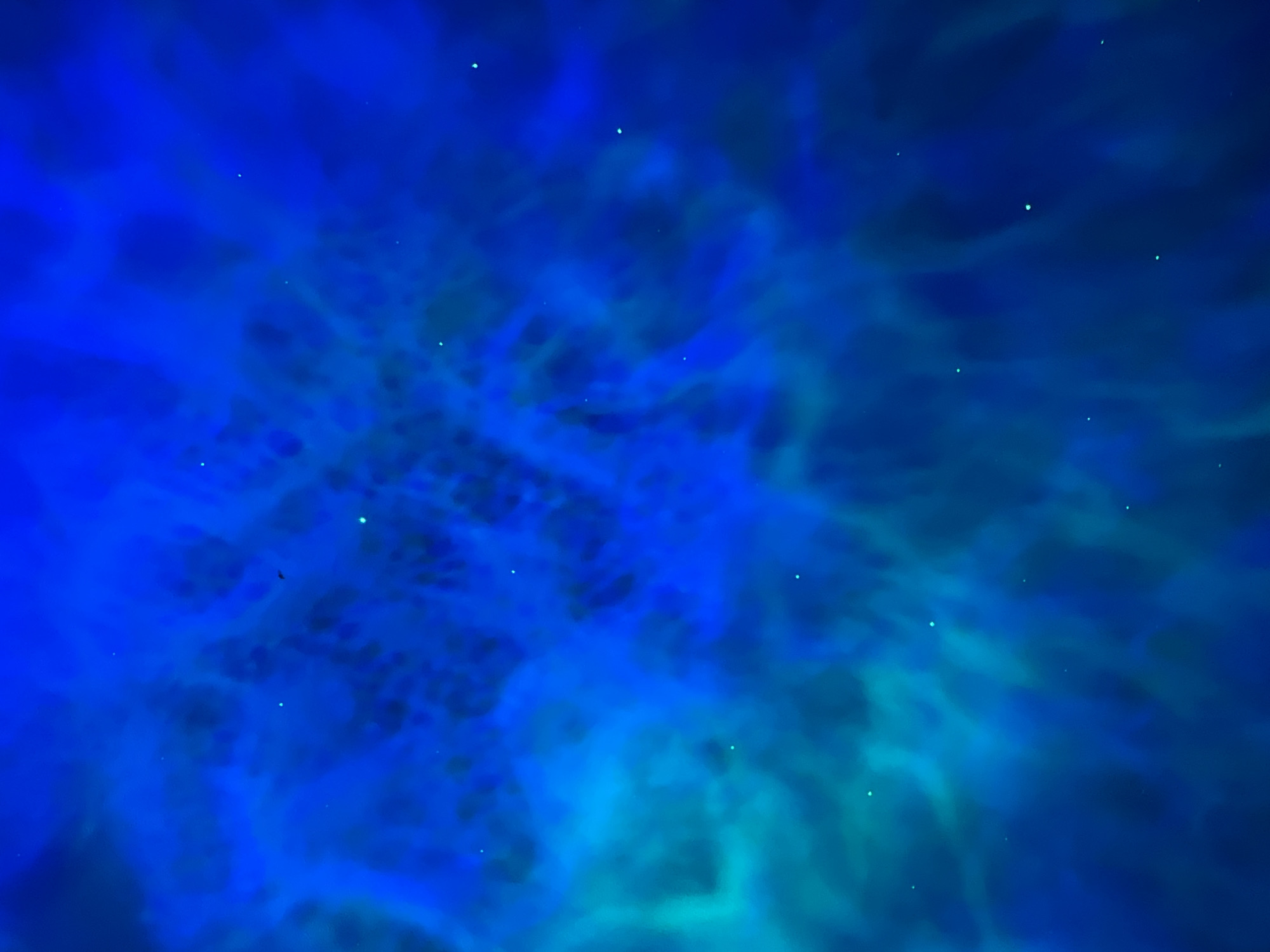 The image is an abstract depiction of a nebula or cosmic cloud, rendered in various shades of blue and hints of turquoise. Wispy, translucent formations create a sense of depth and movement, with small, bright points of light scattered throughout, resembling stars. There is no discernible content that relates to the city of Saint Petersburg, Russia, or any urban environment. The image is entirely abstract and appears to be a digital creation or a photograph of a light effect.