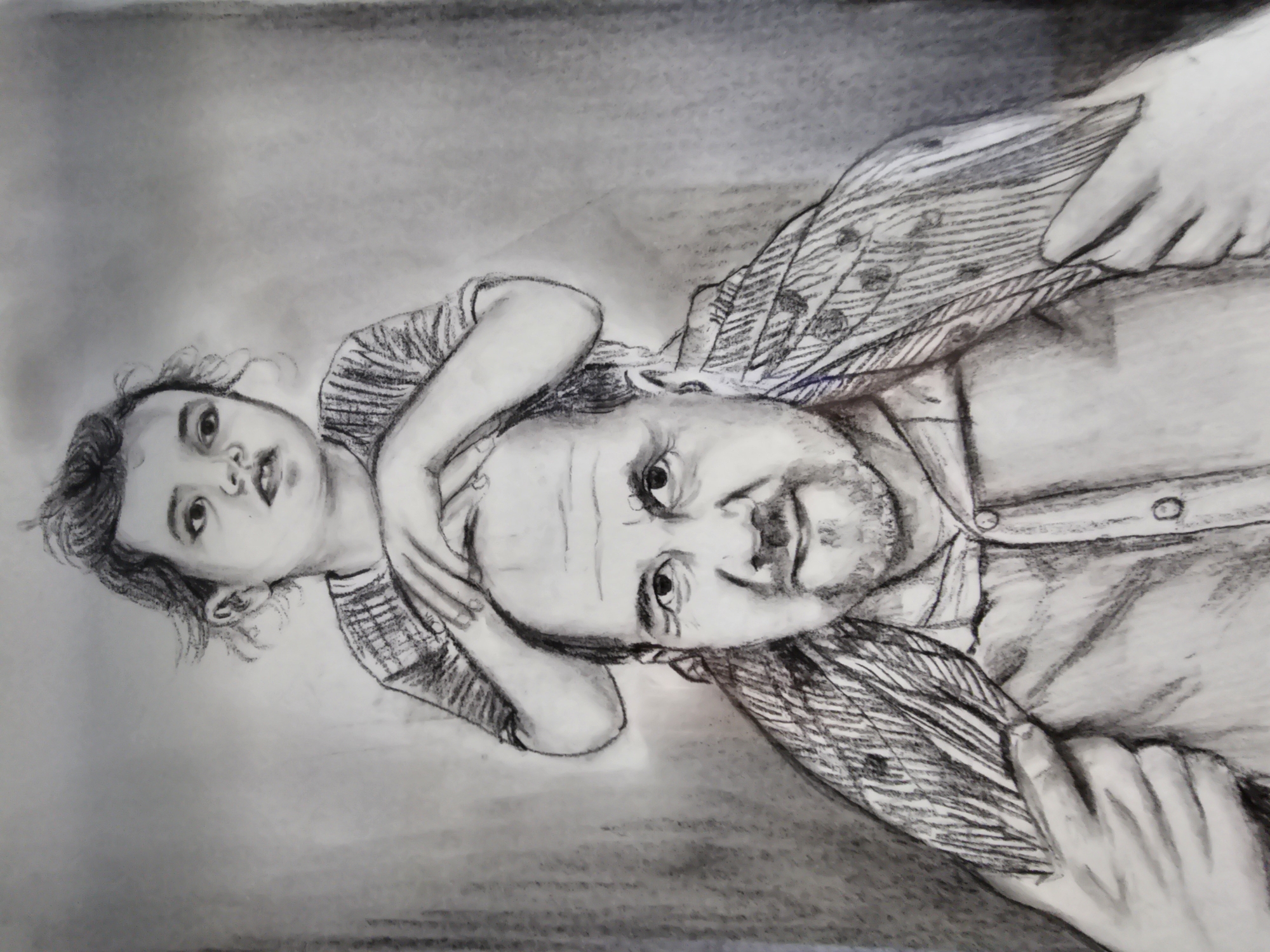 A monochromatic charcoal drawing depicts a man with a child on his shoulders. The scene is described as taking place in the city of Khimki, Russia. The man, appearing middle-aged with a receding hairline and a short beard or goatee, gazes directly at the viewer with a faint smile. He is dressed in a collared shirt with the top button undone, and his hands are visible at the bottom of the frame, appearing to support the child's lower body. Perched atop his shoulders, the child, a toddler or preschooler with dark, curly hair, looks slightly towards the viewer's right with wide, open eyes and a slightly parted mouth. The child's hands are placed on the man's head. The child wears a horizontally striped shirt. The background is a plain, abstract grey wash, devoid of specific environmental details. The drawing utilizes strong lines and varied shading to define the figures, their expressions, and clothing textures.