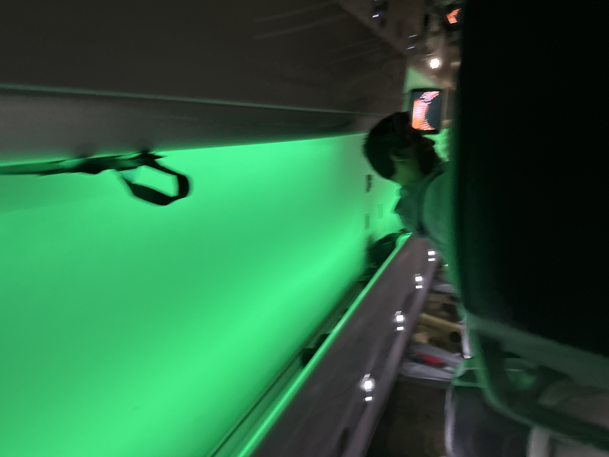 The image appears to be taken inside an airplane cabin. A person is visible in the aisle. The walls are illuminated with a bright green light. There is an overhead luggage compartment.
There is no indication from the image itself where in Varna, Bulgaria this is.