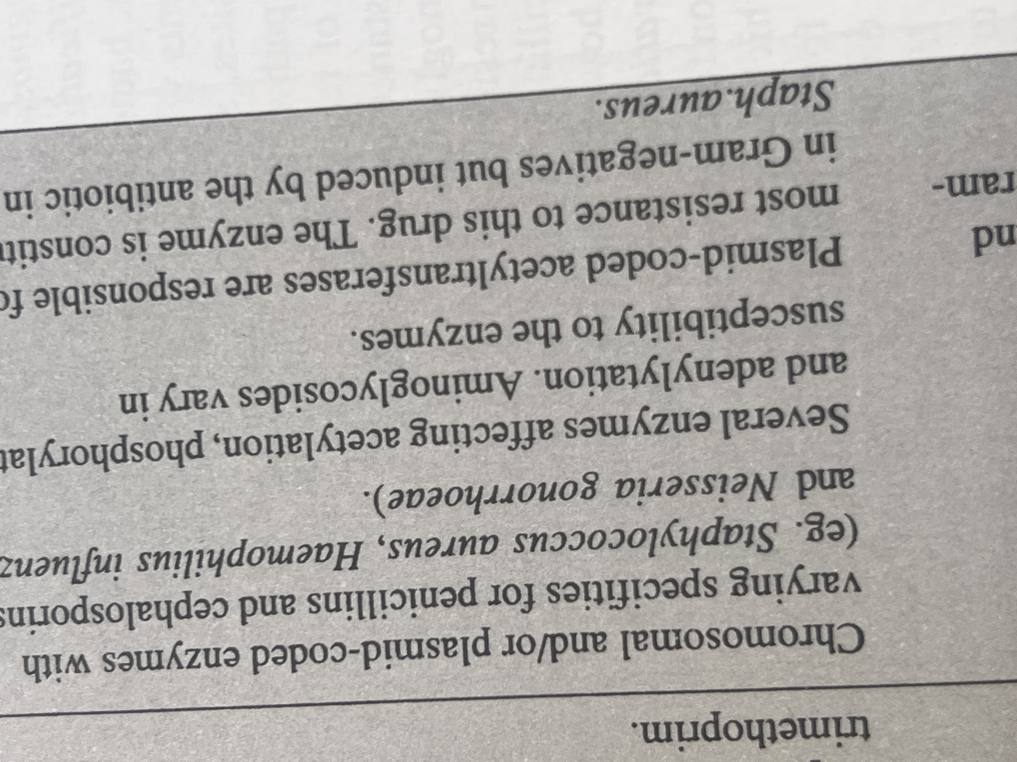 The image shows a close-up of a book page with text. The text is printed in a serif font and is oriented vertically. The page appears to be from a medical or scientific publication, discussing enzymes, antibiotics, and bacterial resistance. There is no visible information within the image that relates to Jauro Yinu, Nigeria, or any specific location.