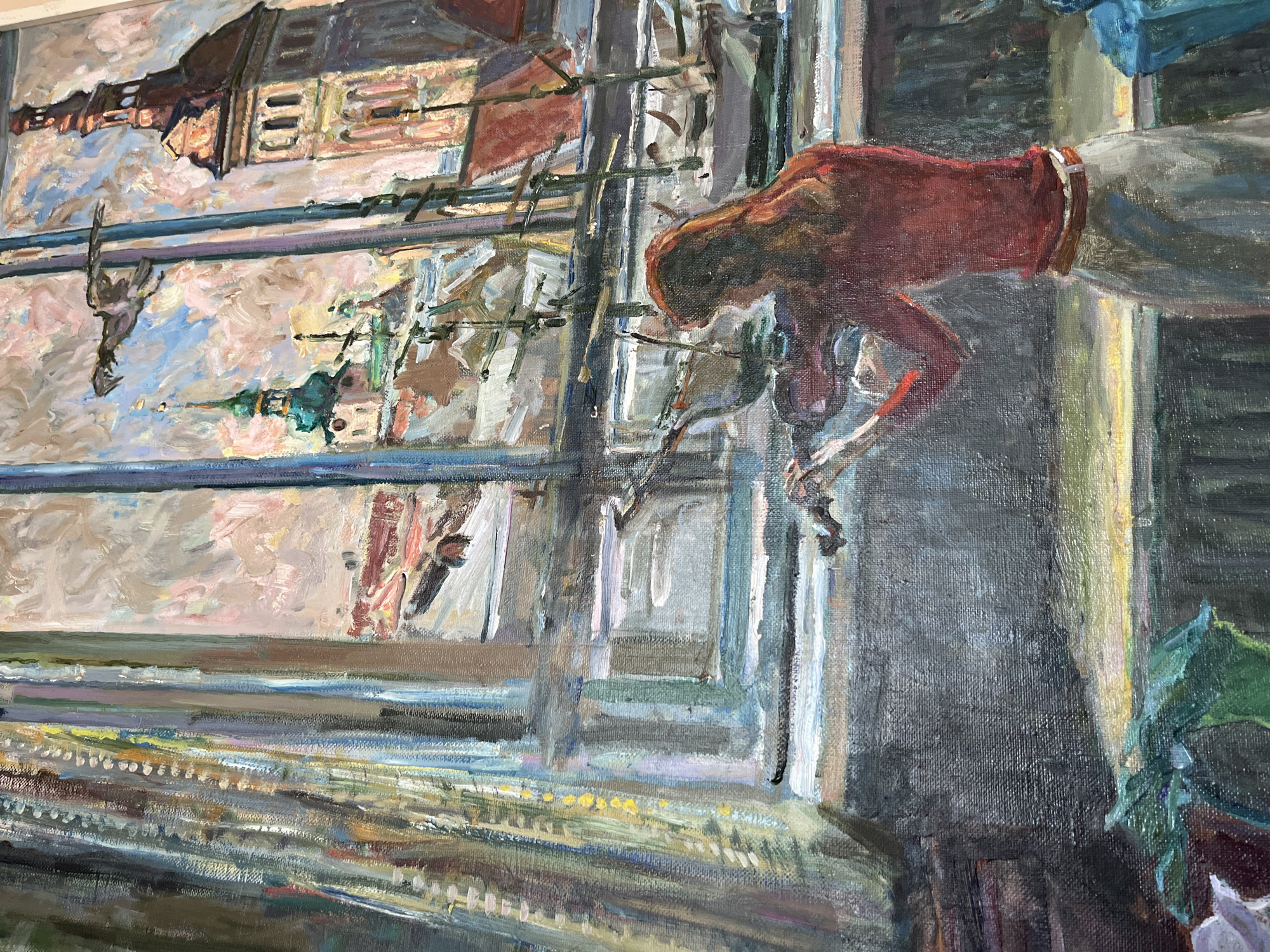 An oil painting depicts a woman playing the violin in an indoor setting, with a view of a city skyline through a window. The woman, with long red hair, wears a reddish-brown top and a light-colored skirt. She is positioned facing the window, her back to the viewer, and her hands are on the violin.
The window looks out onto a cityscape characterized by several prominent buildings. To the right, a tall, multi-story structure with a tower and arched windows is visible, rendered in warm tones of brown and orange. To the left, a building with a green-domed spire rises against a sky filled with impressionistic clouds in shades of pink and blue. The middle ground appears to show rooftops and what might be structures related to a harbor or waterfront, with several boats suggested by their forms. There are also bare trees or masts with rigging in the foreground of the cityscape. A bird in flight is depicted against the sky.
The interior space includes a textured curtain on the left side of the frame, rendered in various shades of blue, brown, and yellow, with visible brushstrokes. The window frame itself is painted in blues and purples. The foreground of the interior shows a dark surface with some green foliage or fabric draped over it.
The painting style is loose and expressive, with visible brushwork and a rich texture. The colors are vibrant but also blended, contributing to a somewhat atmospheric and impressionistic feel. The lighting suggests a daytime scene, with sunlight possibly coming from the window, illuminating the woman's hair and back, and casting warm light on the city buildings.
There is no information within the image or its context to suggest the location is the city of Kohtla-Järve linn, Estonia. The architectural style depicted in the painting appears more characteristic of Central or Western European cities rather than typical Estonian architecture.