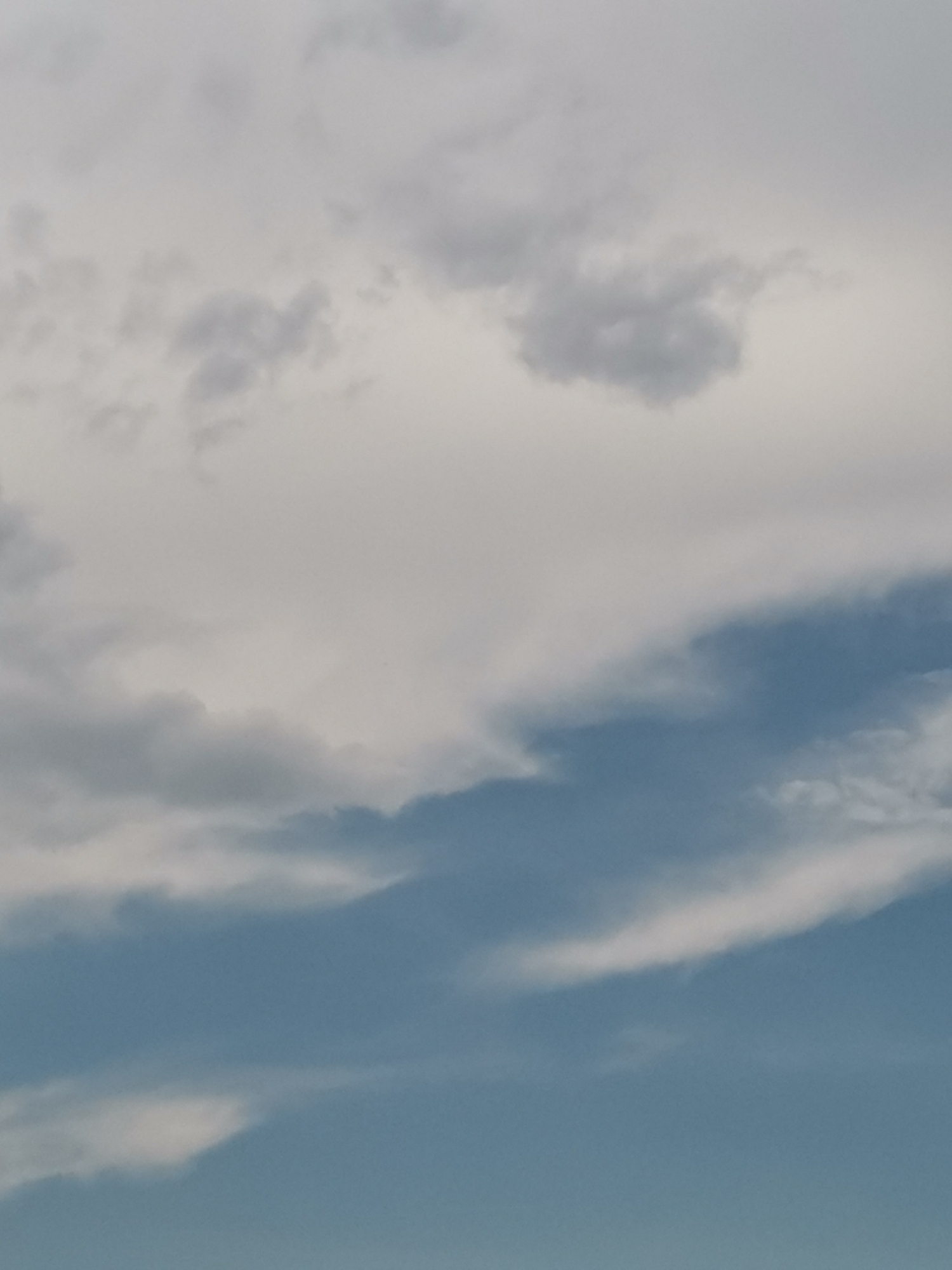 The image shows a portion of the sky with clouds. The clouds are a mix of white and gray, with some appearing wispy and others more dense. The lower portion of the image transitions into a clear blue sky. No buildings, people, or any other identifiable objects are visible. This image is not specific enough to provide any details about its location in the city of Sofia, Bulgaria.