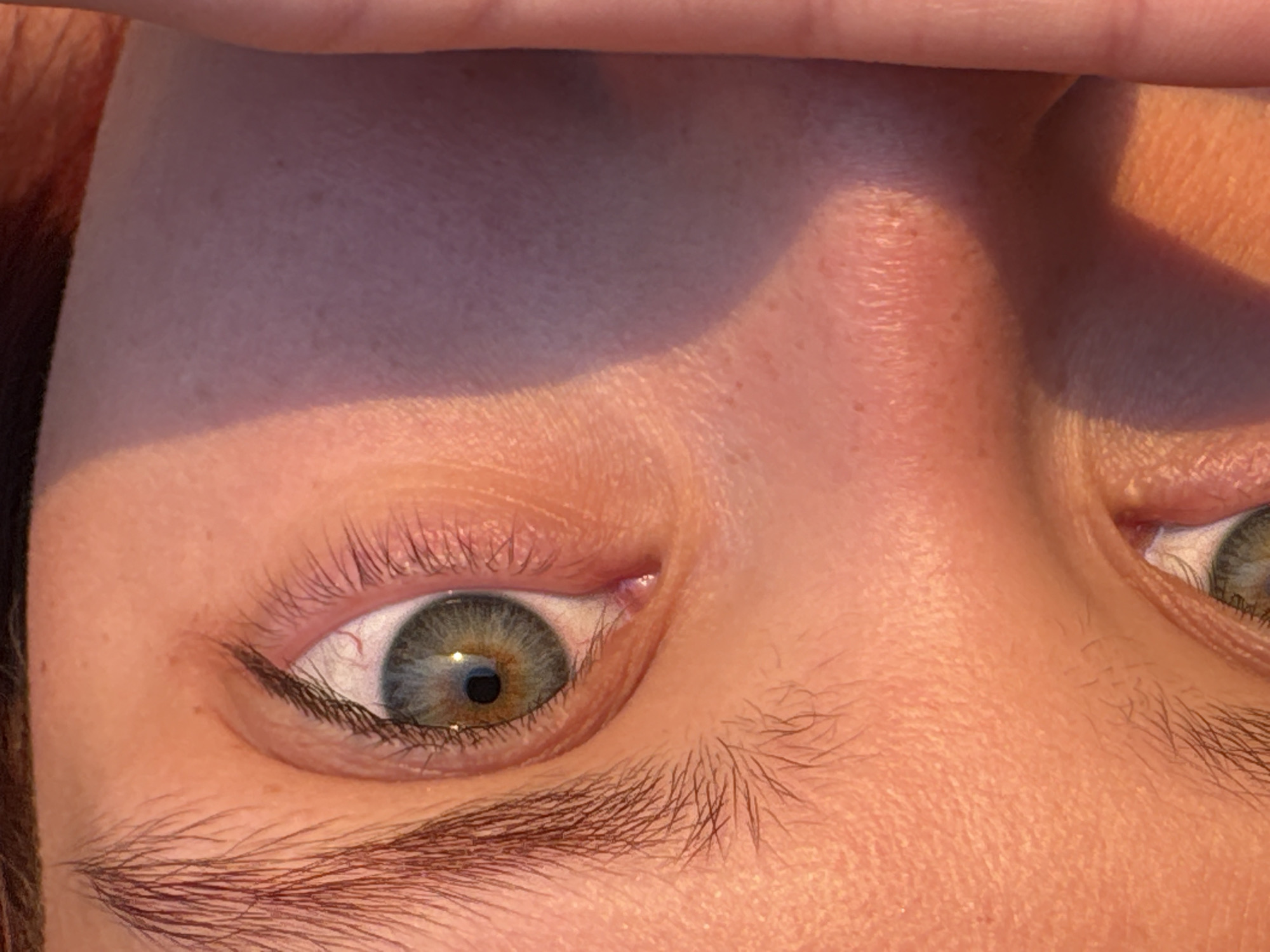 A close-up image captures the eye of a person. The iris is a blend of colors, primarily green and brown. The upper eyelid is visible, lined with dark eyeliner. The lower eyelashes are sparse. The skin appears fair with some visible fine lines. The image is oriented at an angle, as if the subject's head is tilted.
I cannot provide the location in the city of Прикамский, Russia because the picture does not contain such information.