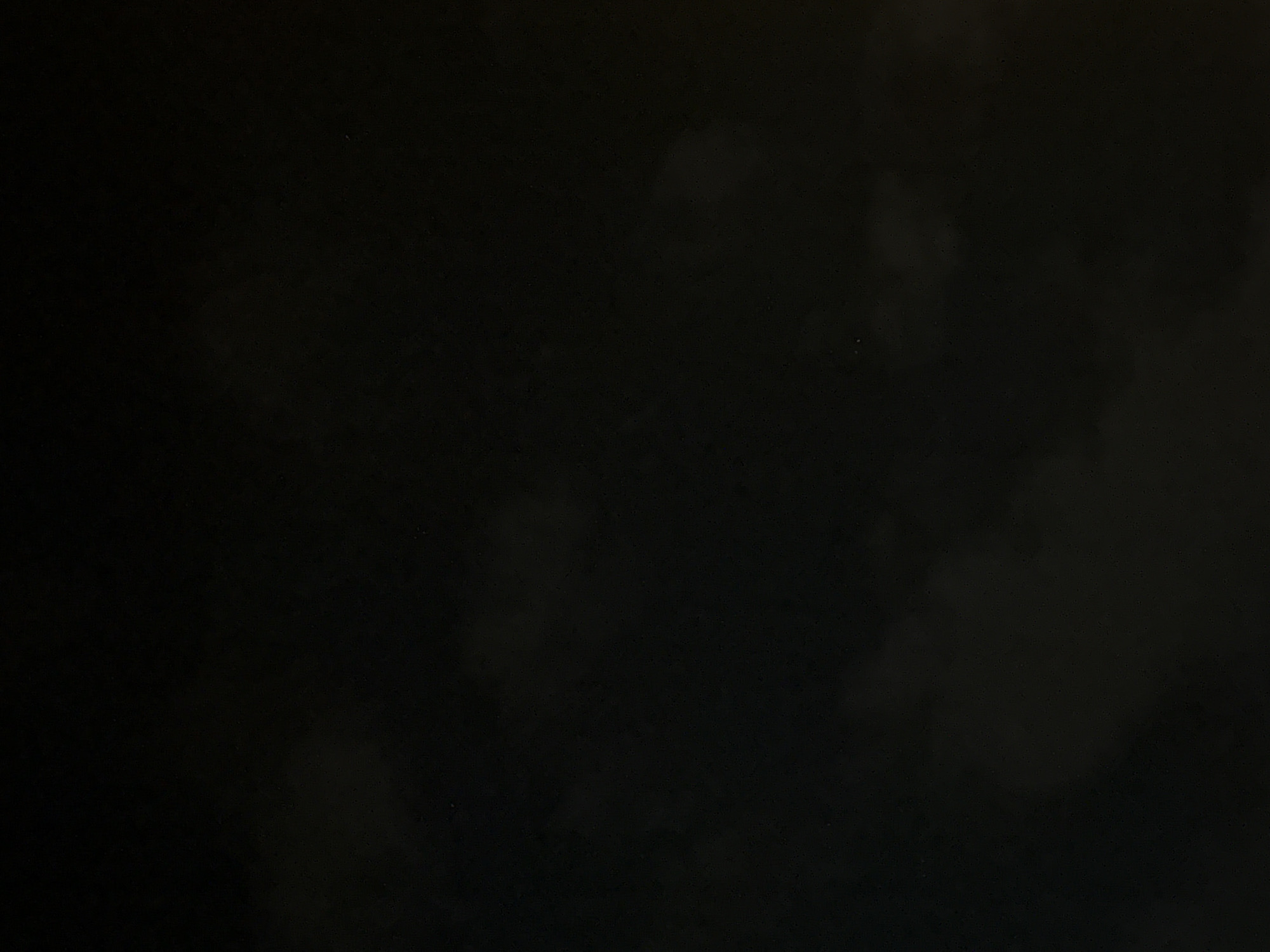The image is a dark, underexposed photograph of a cloudy night sky with a faint glow on the right side, possibly from artificial lighting. There are no discernable structures, people, or objects visible in the image, making it impossible to determine its location within Boreti, Montenegro, or any other specific environment. The image is predominantly black with some lighter, amorphous shapes suggesting clouds.
