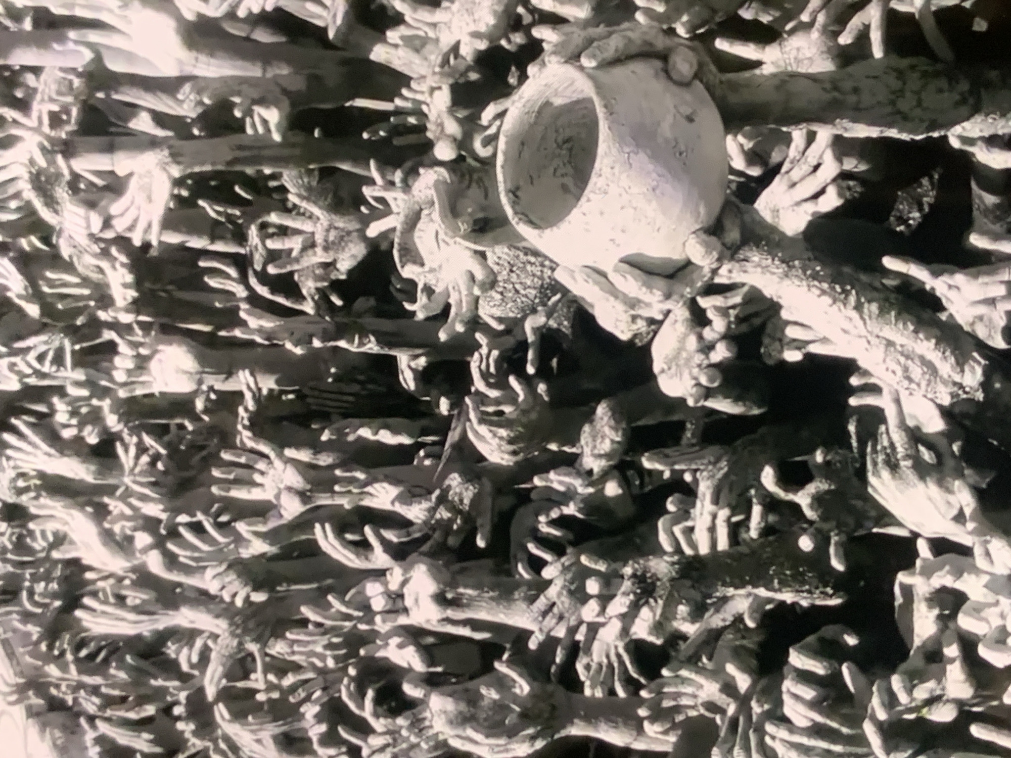 The image displays a large, dense arrangement of sculpted hands and arms emerging from a dark, textured surface. The sculptures are in various states of completion and detail, with some appearing more fully formed than others. Many of the hands are reaching upwards, with open palms and spread fingers, suggesting a sense of desperation or supplication. The overall tone is monochromatic, with a strong contrast between light and shadow, creating a dramatic and somewhat eerie effect.
The image is not taken in Stavropol, Russia. The depicted scene is the "Hands of Hell" at the Wat Rong Khun (White Temple) in Chiang Rai, Thailand. This art installation is a contemporary interpretation of Buddhist cosmology and symbolism, representing the torment of souls in hell reaching out for salvation.