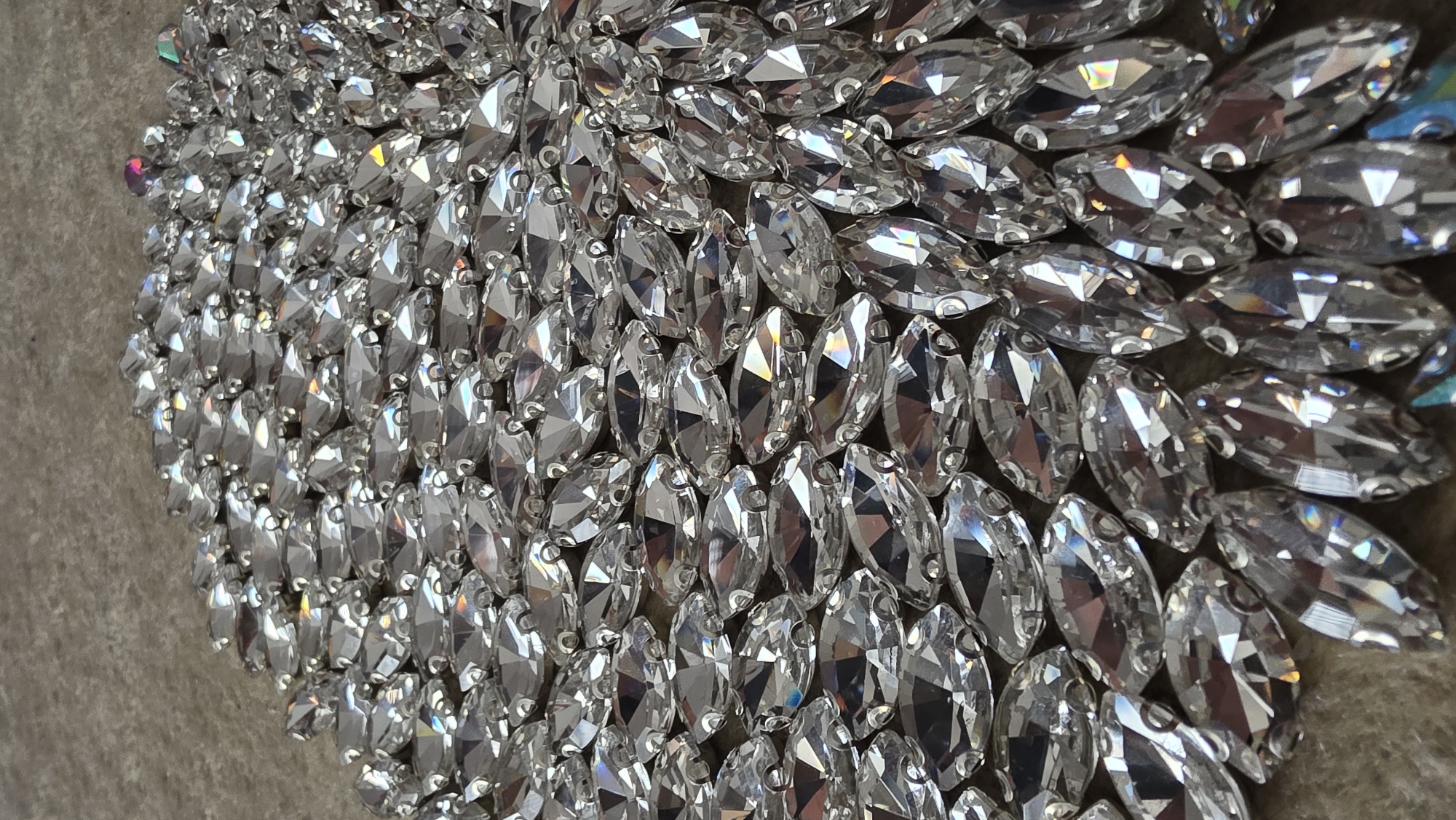 The image shows a dense cluster of clear, marquise-cut rhinestones arranged to form a rounded shape. The individual stones are tightly packed and appear to be glued or adhered to a flat surface. The rhinestones reflect light, creating numerous bright highlights and shadows. The overall impression is one of a sparkling, textured surface. There is no evidence in the image to indicate it is in Blagoevgrad, Bulgaria.