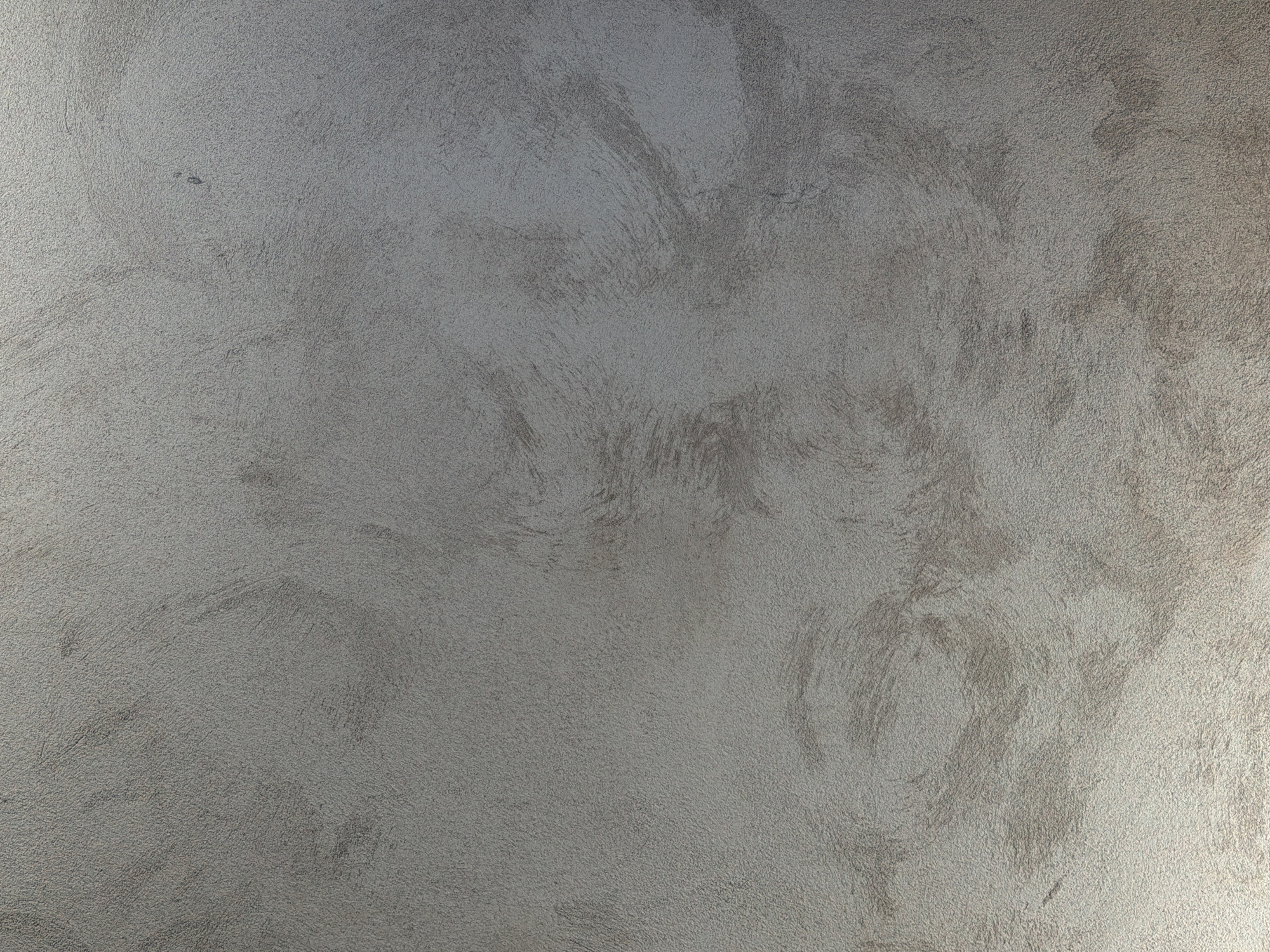 The image is a close-up, full-frame shot of a textured, gray wall with subtle swirling patterns. The texture appears to be a fine-grained plaster or stucco, with variations in sheen suggesting different angles of light catching the surface. There are no people, objects, or discernible environmental features visible within the frame. The lighting is soft and diffuse, creating a slightly gradient effect from the brighter bottom to the darker top. This image does not provide any information about the city of Piacenza, Italy, or any specific location within it.