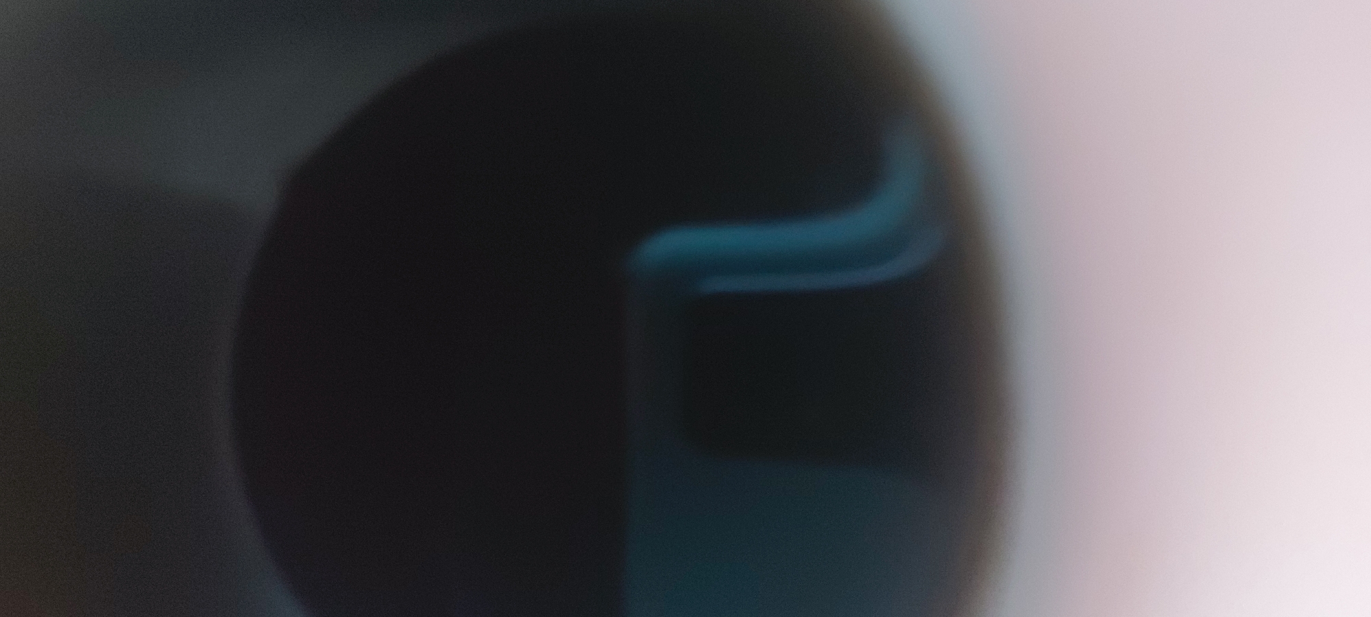 The image is an out-of-focus photograph. It features a large, dark, blurry mass that dominates the left side of the frame. The right side of the image fades into a light pink or white color. Within the dark mass, there is a section with a blueish hue and a curved shape. The image is unclear and lacks detail. There is no indication that the image was taken in Tashkent, Uzbekistan.