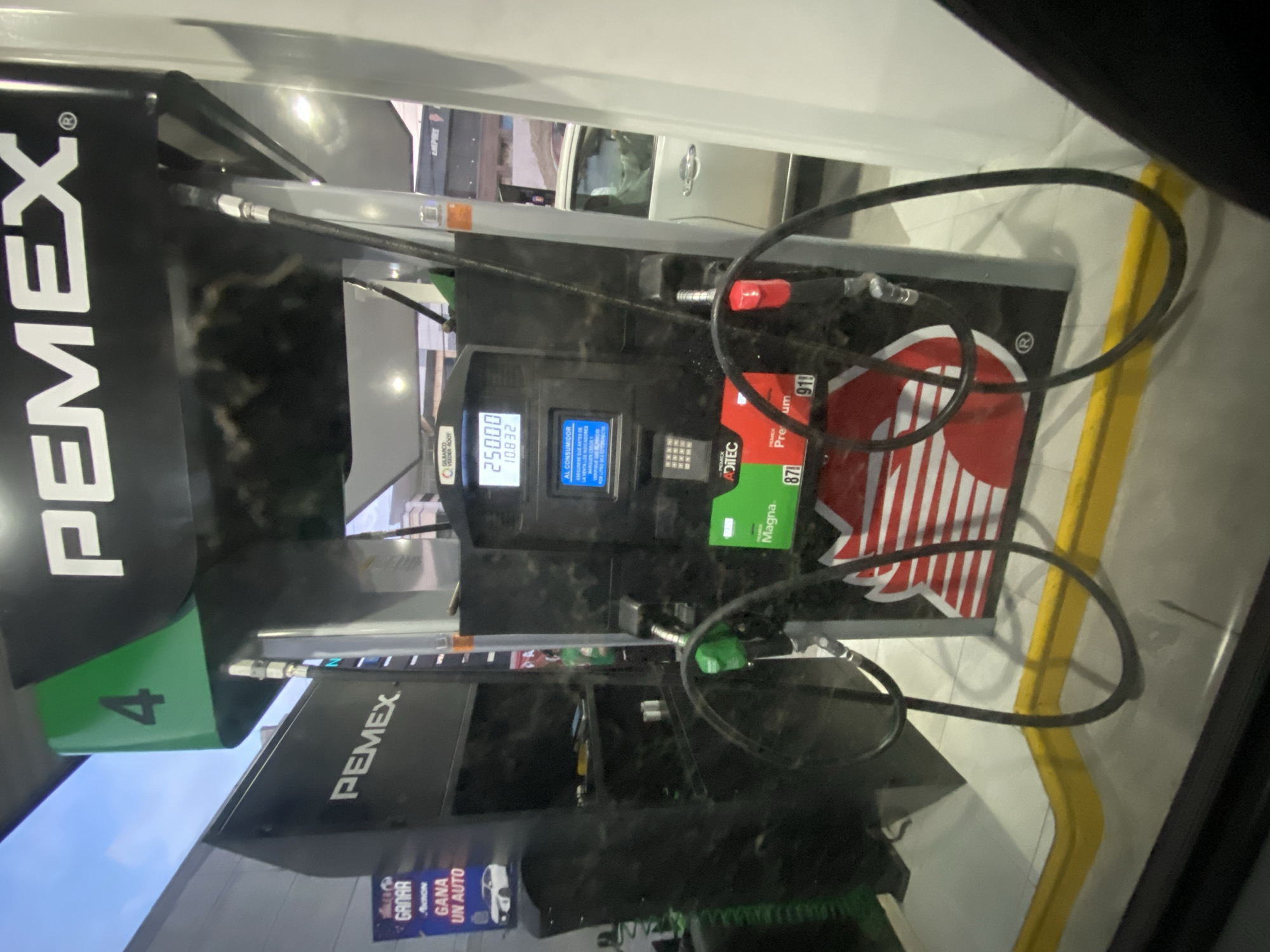 The image depicts a Pemex gas pump, identified by the green "4" and "PEMEX" branding. The pump shows a transaction of 250.00 (likely pesos), with 10.832 units dispensed. Promotional material is visible, offering a chance to win a car. Gas types, Magna and Premium, are indicated on the pump.