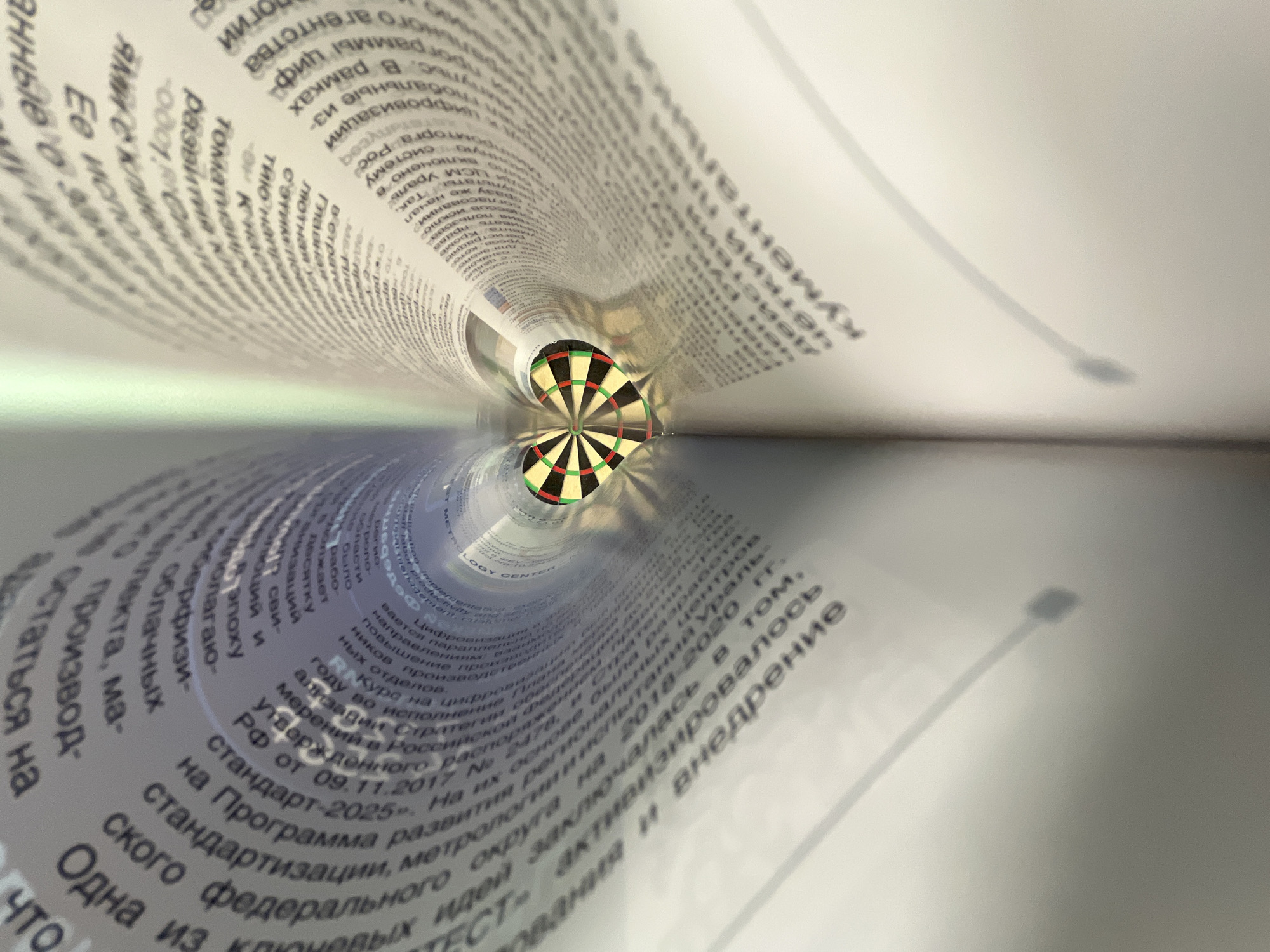 A fisheye lens perspective captures a dartboard at the vanishing point of a tunnel formed by rolled-up sheets of paper with Cyrillic text. The paper's reflection creates a mirrored tunnel effect. The text appears to be about digitalization and standardization in the Russian Federation. The "LOGY CENTER" is also visible within the tunnel. The location Chaikovsky, Russia, is not discernible from the image.