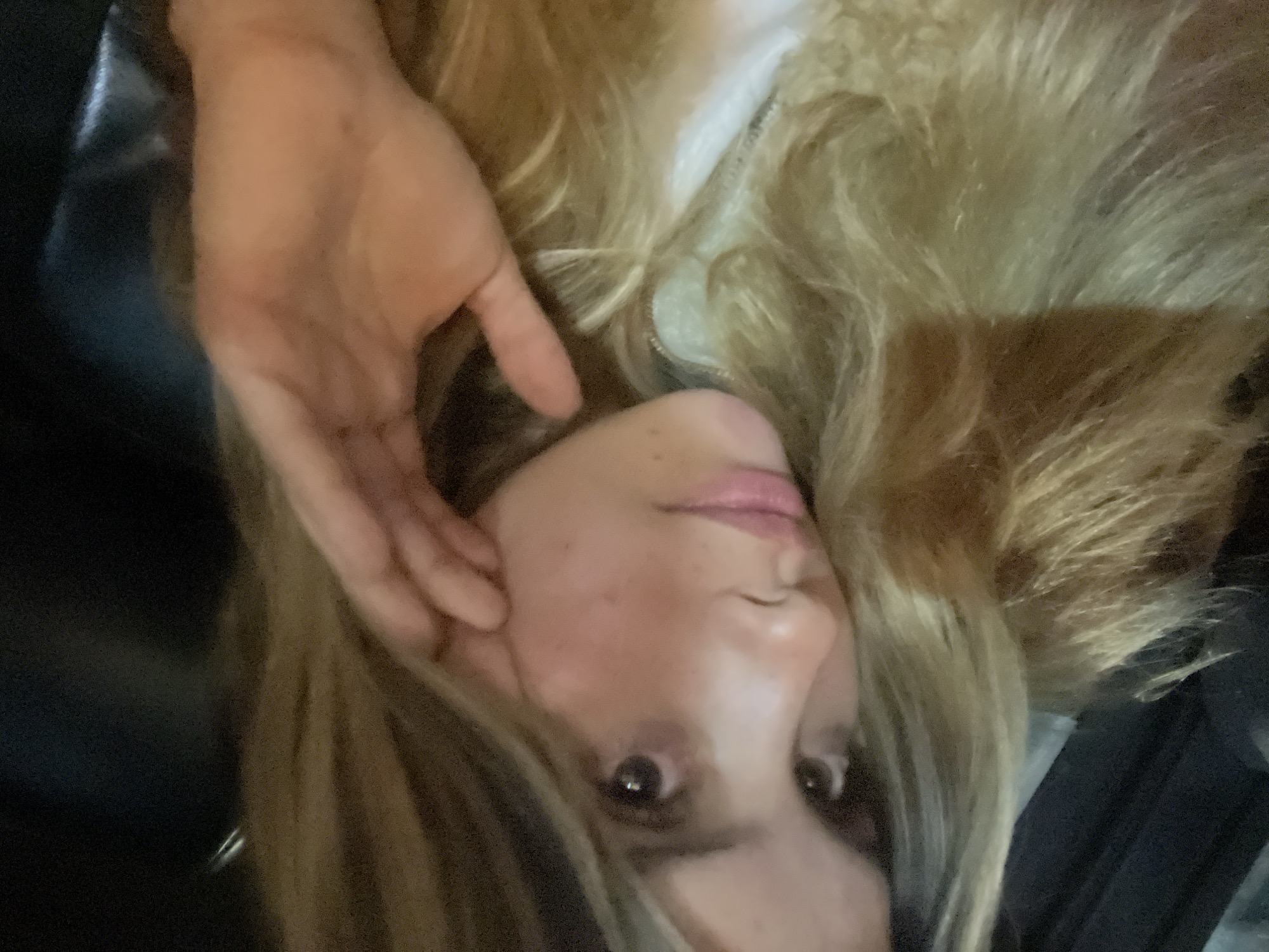 A person with fair skin and light brown or blonde hair is visible. The individual is gazing at the camera with a hand near their face. The hair appears to be layered. The background is dark and indistinct. The location in the city of San Fernando del Valle de Catamarca, Argentina is not discernible from the image.