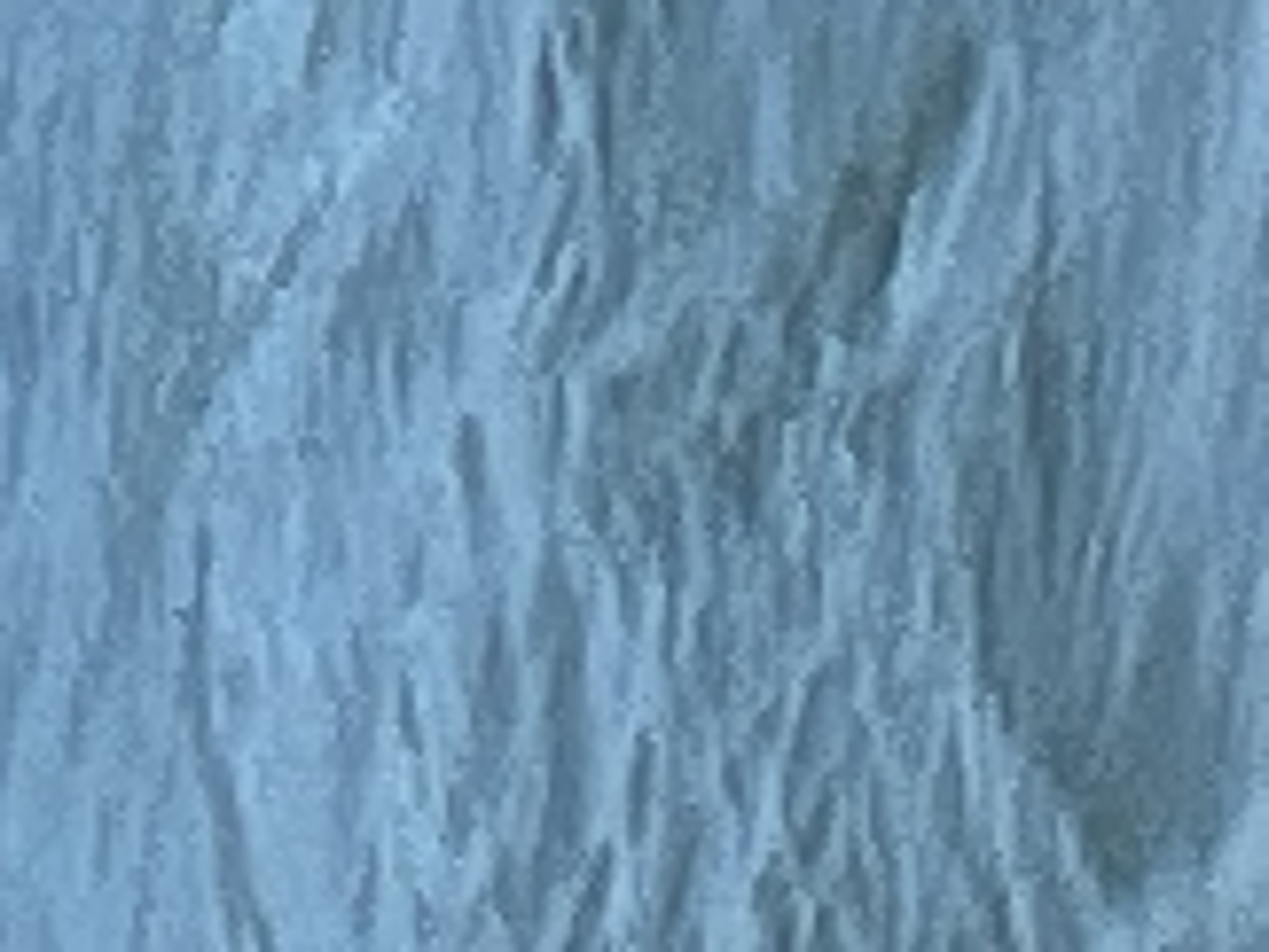 The image depicts a close-up, abstract view of choppy, blue water. The texture suggests movement, with small waves and ripples creating patterns of light and shadow across the surface. There are no discernible objects, people, or specific landmarks visible, making it impossible to determine a location within Constanța, Romania, or any other specific place.