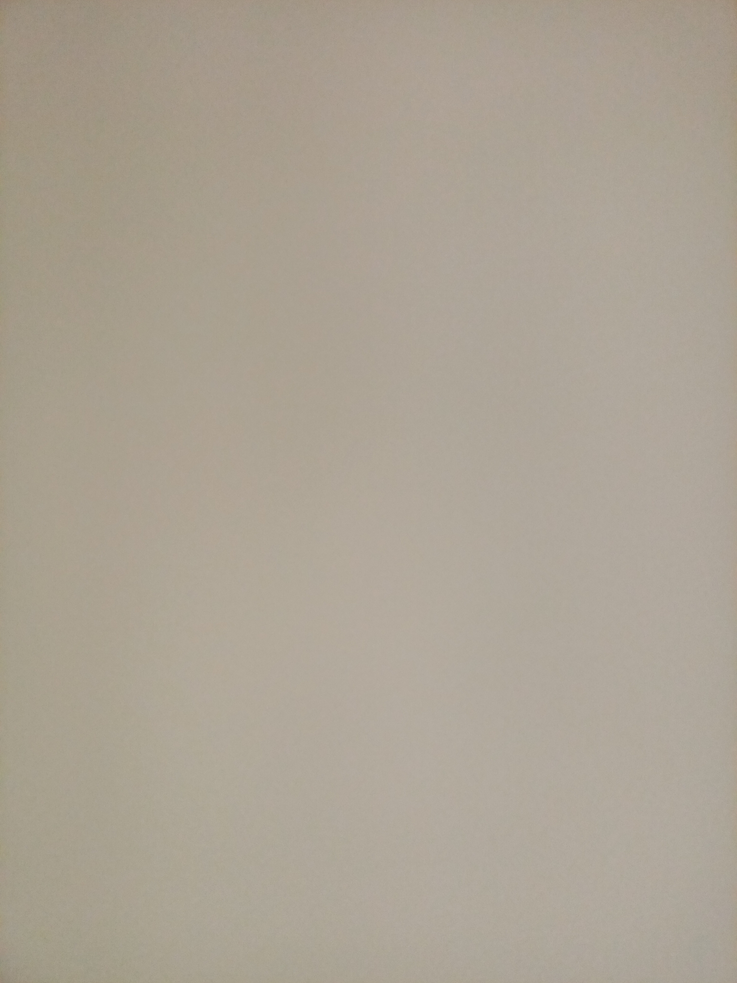 The image is a plain, textured, light beige or taupe background. There are no discernable subjects, objects, people, actions, interactions, or environmental details visible. The image appears to be a photograph of a blank surface, such as a wall or a piece of paper, with slight variations in lighting and texture. There is no information within the image to suggest a location in Rostov-on-Don, Russia.