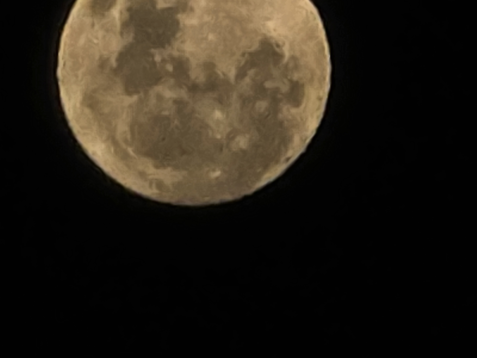 The image shows a full moon in the night sky. The moon is centered at the top of the frame, its surface displaying variations in shading. The background is a solid, dark black. There are no visible landmarks or features indicating the location is Yambol, Bulgaria.
