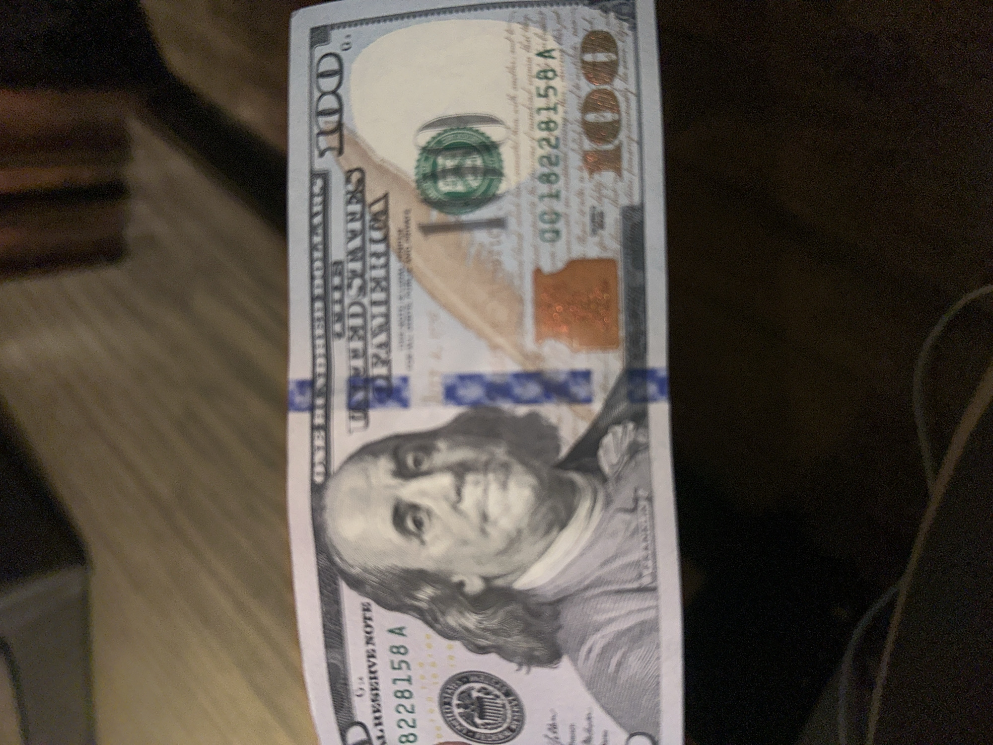 The image shows a United States one hundred dollar bill. The bill is partially visible and features Benjamin Franklin's portrait. The serial number is 0018228158 A. The bill appears to be lying on a surface, but no other details about the surroundings are visible. No information suggests that this image was taken in Yerevan, Armenia.