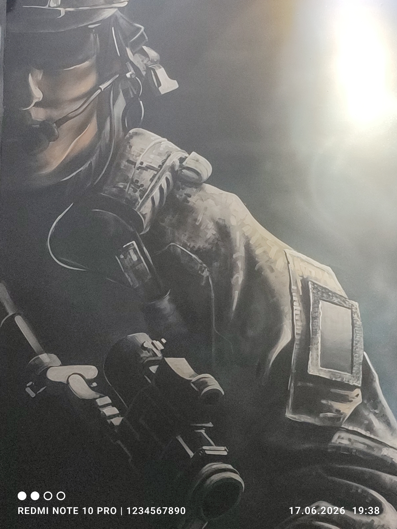 The media file depicts a close-up, stylized painting of a soldier in tactical gear, likely a portrait or a section of a larger artwork. The soldier is wearing a helmet, goggles, and a microphone headset. Their uniform is detailed with camouflage patterns and appears to be made of heavy fabric. A rifle scope or similar optical device is prominently featured in the foreground, suggesting the soldier is armed and ready.
The lighting in the artwork is dramatic, with a bright, almost blown-out light source originating from the upper right, casting strong highlights and deep shadows. This creates a sense of intensity and possibly a dramatic or action-oriented atmosphere. The background is dark and somewhat abstract, with a smoky or misty effect, further enhancing the mood.
Visible text at the bottom left of the image reads "REDMI NOTE 10 PRO | 1234567890". In the bottom right corner, a timestamp is displayed: "17.06.2026 19:38". These textual elements are likely metadata from the device used to capture the image of the artwork, rather than being part of the artwork itself. The location context of Fergana City, Uzbekistan, provides a geographical setting for where the image was taken, but does not appear to be depicted within the artwork. The artwork itself doesn't convey specific time of day, weather, or emotional states beyond a general sense of focus or readiness associated with the soldier's depiction.