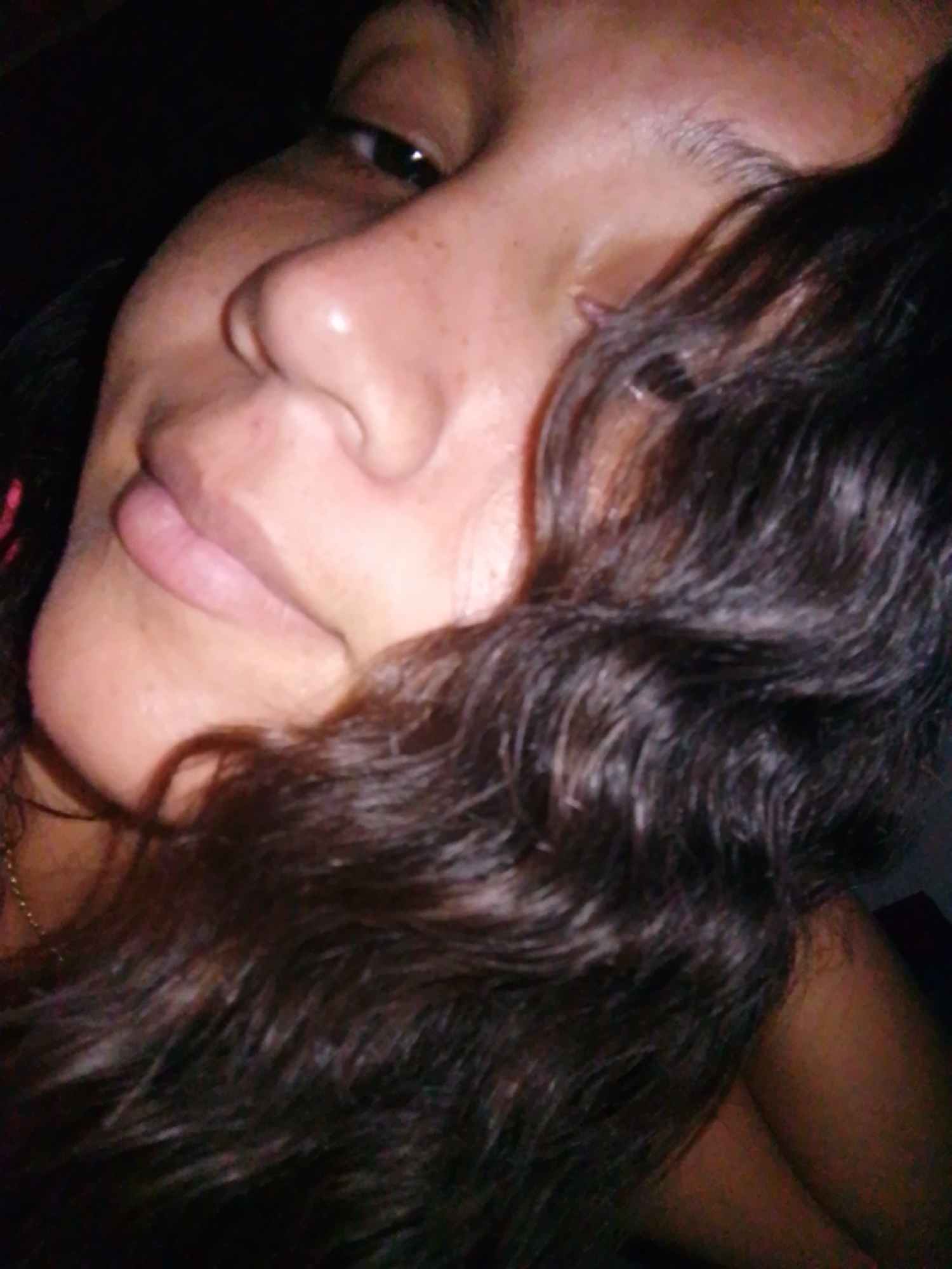 A close-up photograph shows a person with brown, curly hair partially covering their face. The person has a light skin tone and appears to be lying down. The background is dark and indistinct. There is no indication of a location or any interaction. The image is focused on the person's face and hair. The city of Juan Griego, Venezuela, is not evident in the image.