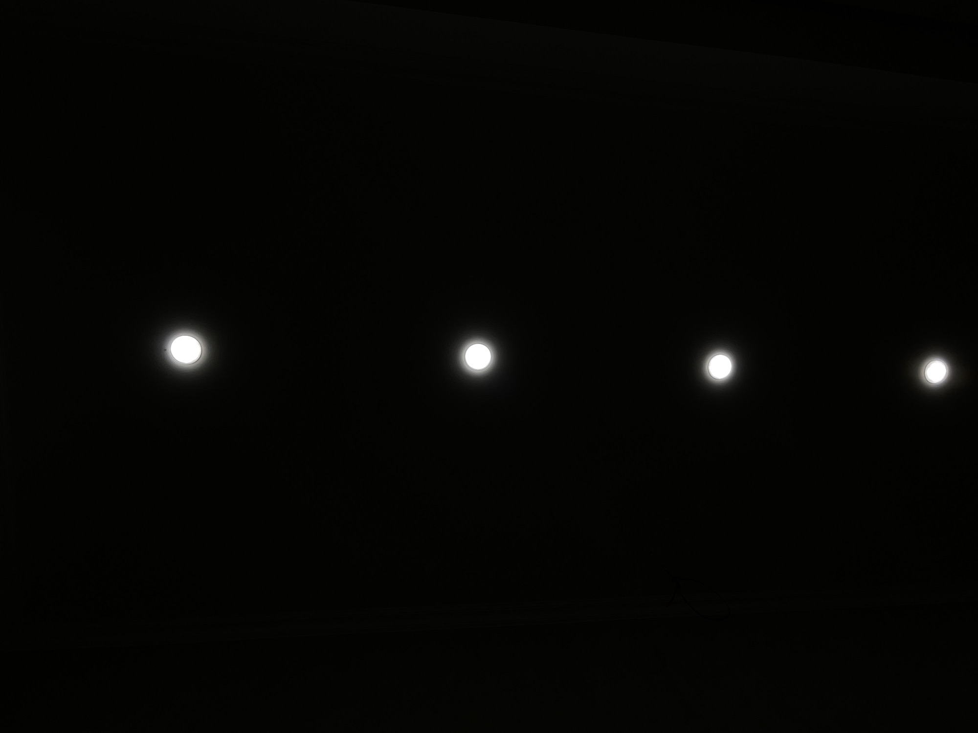 The image depicts a dark, abstract composition featuring five circular, white lights evenly spaced vertically against a black background. The lights appear to be illuminated, possibly light bulbs or LEDs, and are the sole visible elements of interest. The scene is devoid of any contextual elements that would suggest a specific location, time, or narrative. Therefore, it is impossible to determine the city of Tbilisi, Georgia, or any other specific geographical context from the provided image.