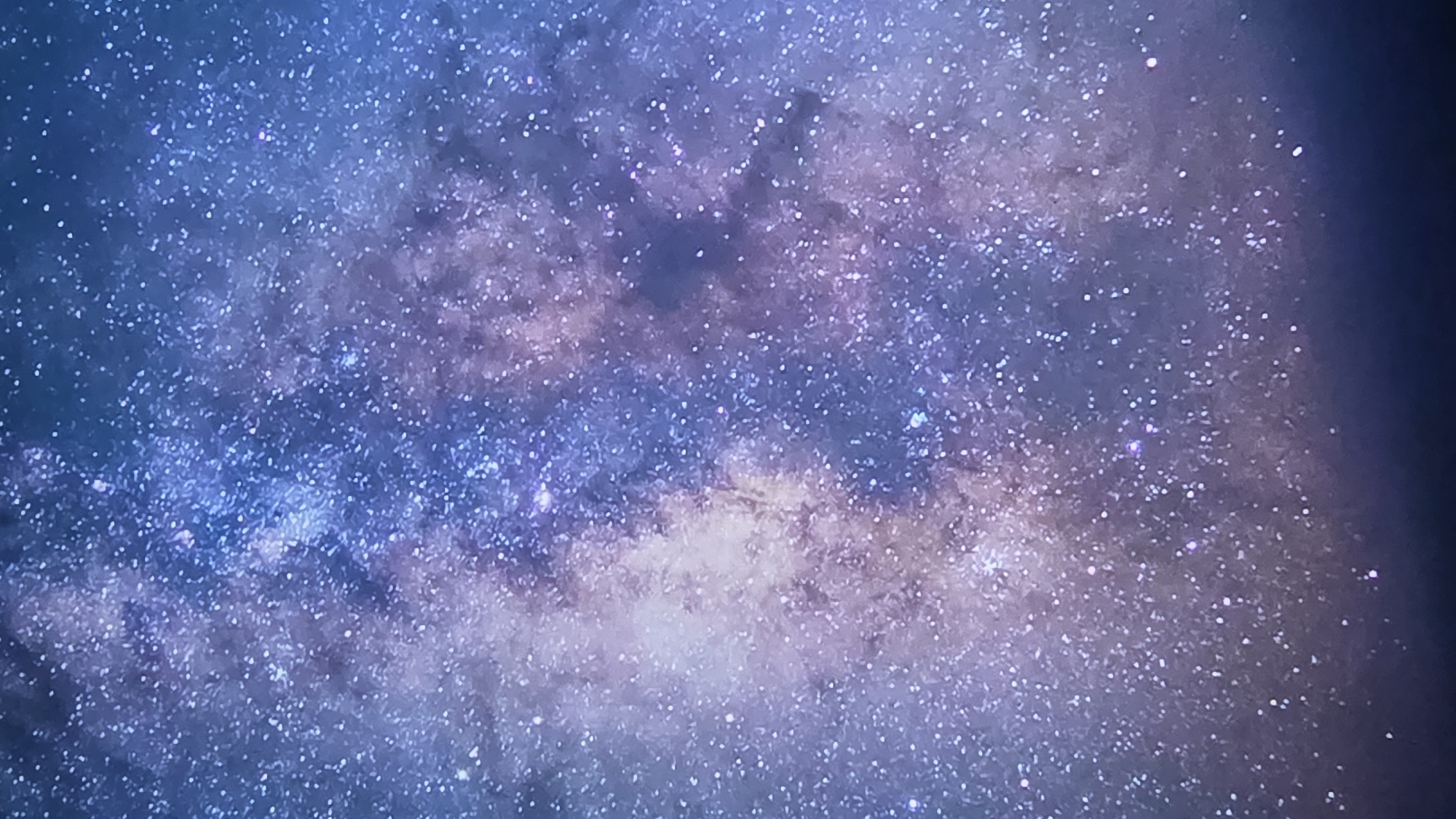 The image is a close-up view of the Milky Way galaxy, displaying a dense collection of stars and nebulae. The colors are predominantly deep blues and purples, with brighter white and pinkish hues scattered throughout, indicating the luminescence of stars and gas clouds. The composition is abstract, focusing on the celestial bodies without any discernible foreground or background elements that would suggest a specific location on Earth. Therefore, it is not possible to identify any details related to the city of East Jakarta, Indonesia, as the image depicts a view of outer space.