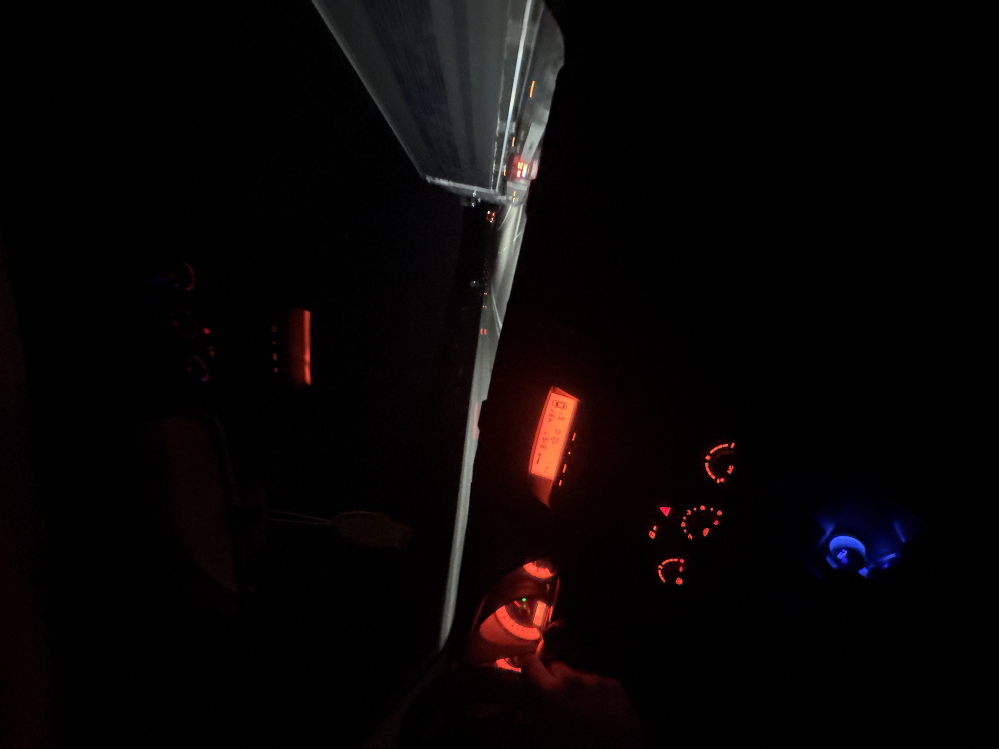 The image shows the interior of a car at night. The dashboard is visible, with illuminated gauges and displays in red and blue. The car appears to be stationary, facing a large truck or trailer, judging by the reflected lights at the top of the frame. The location in Krushovitsa, Bulgaria is not discernible from the visual content.